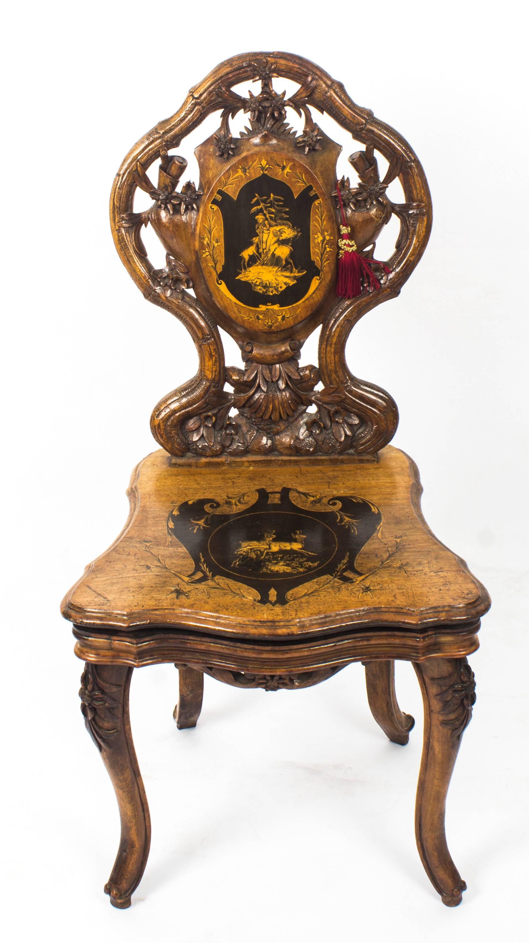 This is a superb antique 19th century Swiss carved walnut and marquetry inlaid musical chair.

It has a striking branch and leaf patterned back which is centred by a cartouche decorated with a figure and two goats, the hinged seat also decorated