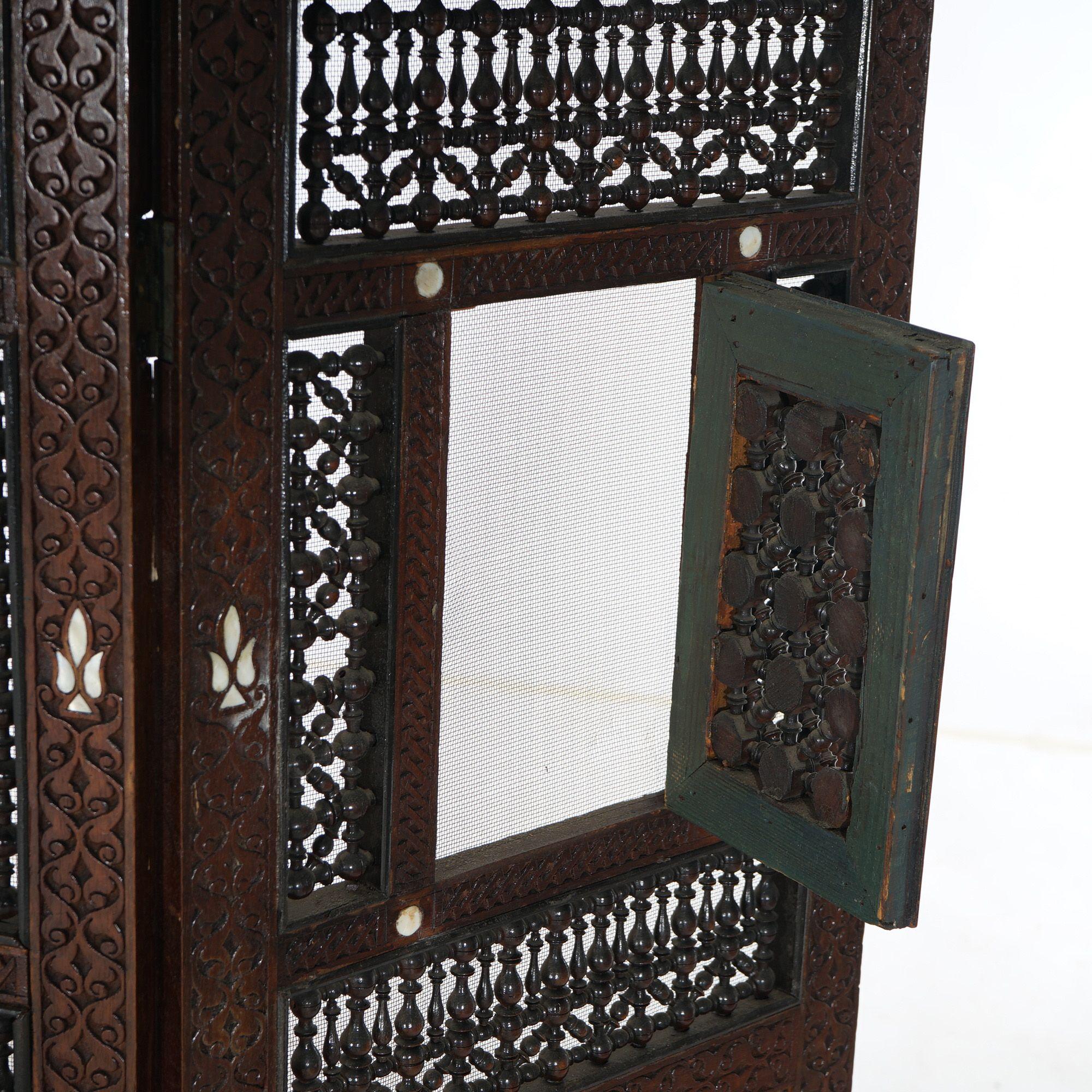 An antique Syrian screen offers carved hardwood construction with mother of pearl inlaid accents, center panel having hinged door, and Crescent moon form finials, 19th century

Measures - 46.5