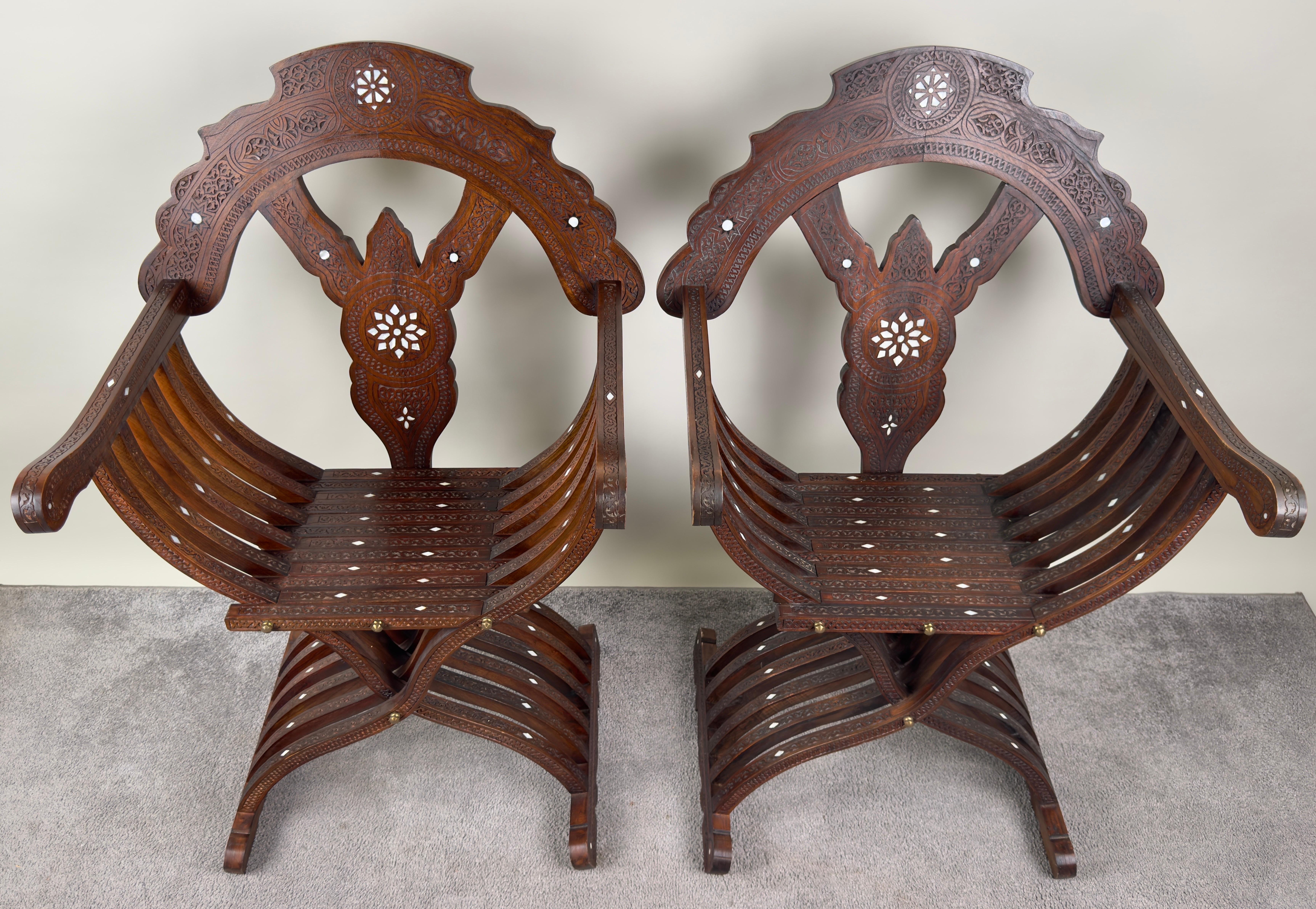 Cette exquise paire de fauteuils trône en Curule syrienne Savonarola du XIXe siècle représente le summum de l'artisanat ancien et du raffinement esthétique. Les chaises présentent des incrustations complexes de nacre, méticuleusement incorporées