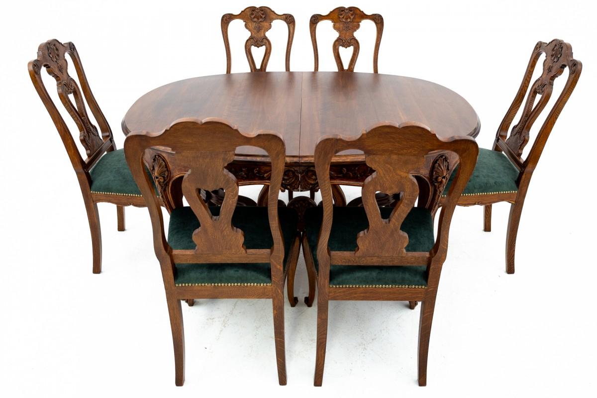 Antique carved table with 6 chairs. It comes from the end of the 19th century in Western Europe. The solid oak chairs are upholstered in new dark green fabric and finished with decorative copper upholstery nails. The table has an additional insert