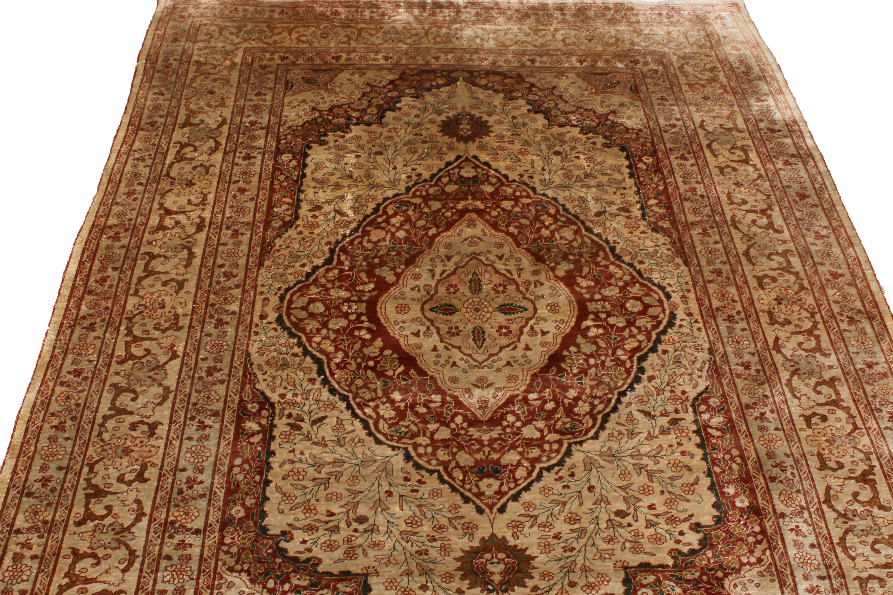 Hand-knotted in a lightly distressed, luminous silk body originating from Persia in 1900, this antique Tabriz Persian rug enjoys an uncommon dimensionality in the pairing of this rare beige and pink colorways with an intricate field and border