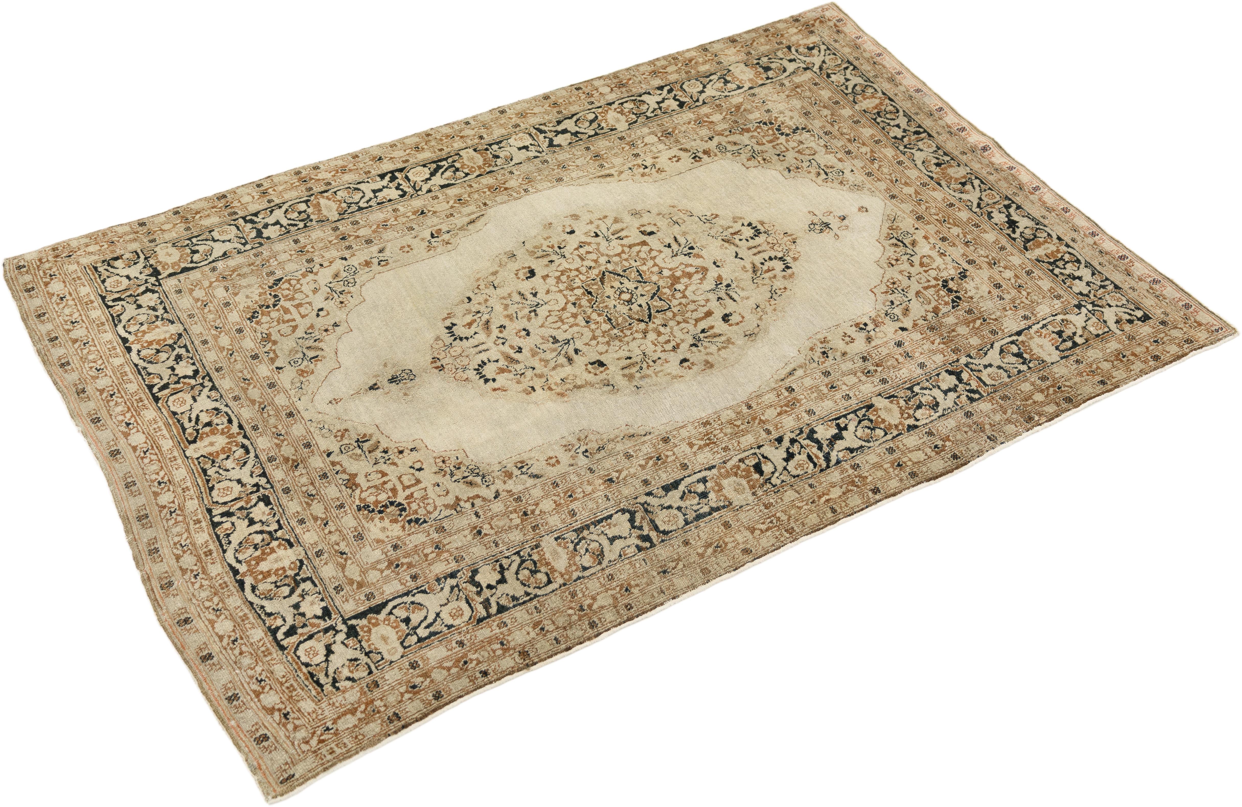 Hand-knotted Tabriz Haj Jalili rug, woven in Northwest Iran circa 1900.

This antique Haj Jalili Tabriz rug features an elegant central medallion set within a softly shaded beige field, framed by intricate borders in taupe and muted blue tones. The