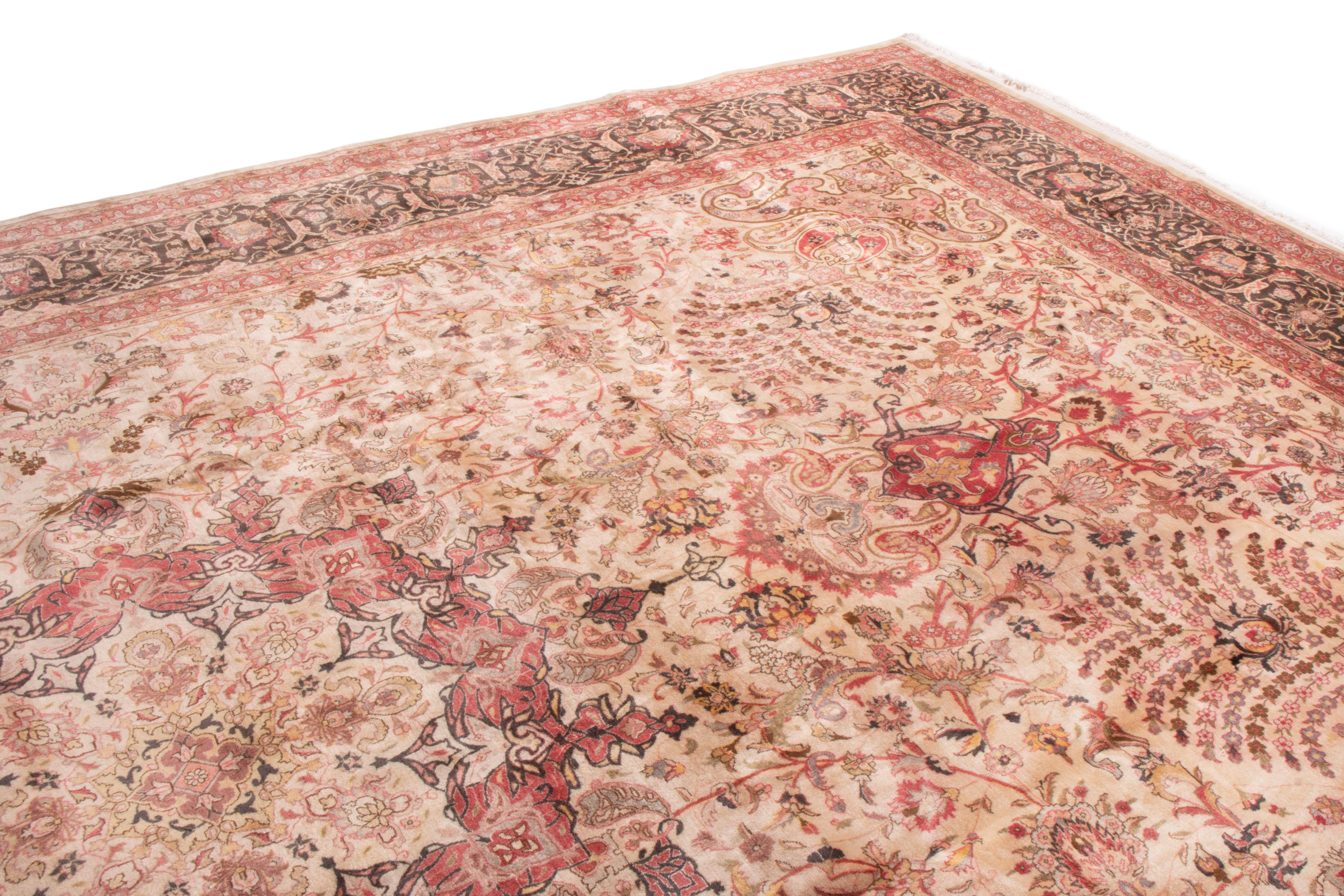 This antique Tabriz wool rug has originates from India in the 1960s. The uncommon choice of pink is accented by burgundy and beige throughout the field and border, both of which feature transitional curvilinear garlands and vine scroll patterns. As