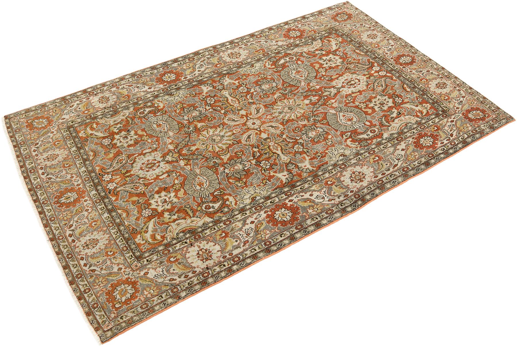 Hand-knotted Tabriz rug, woven in Northwest Iran circa 1940.

This Tabriz rug presents a beautifully detailed floral pattern arranged symmetrically across a rust-colored field, framed by a soft beige border with subtle gray and ivory accents. The