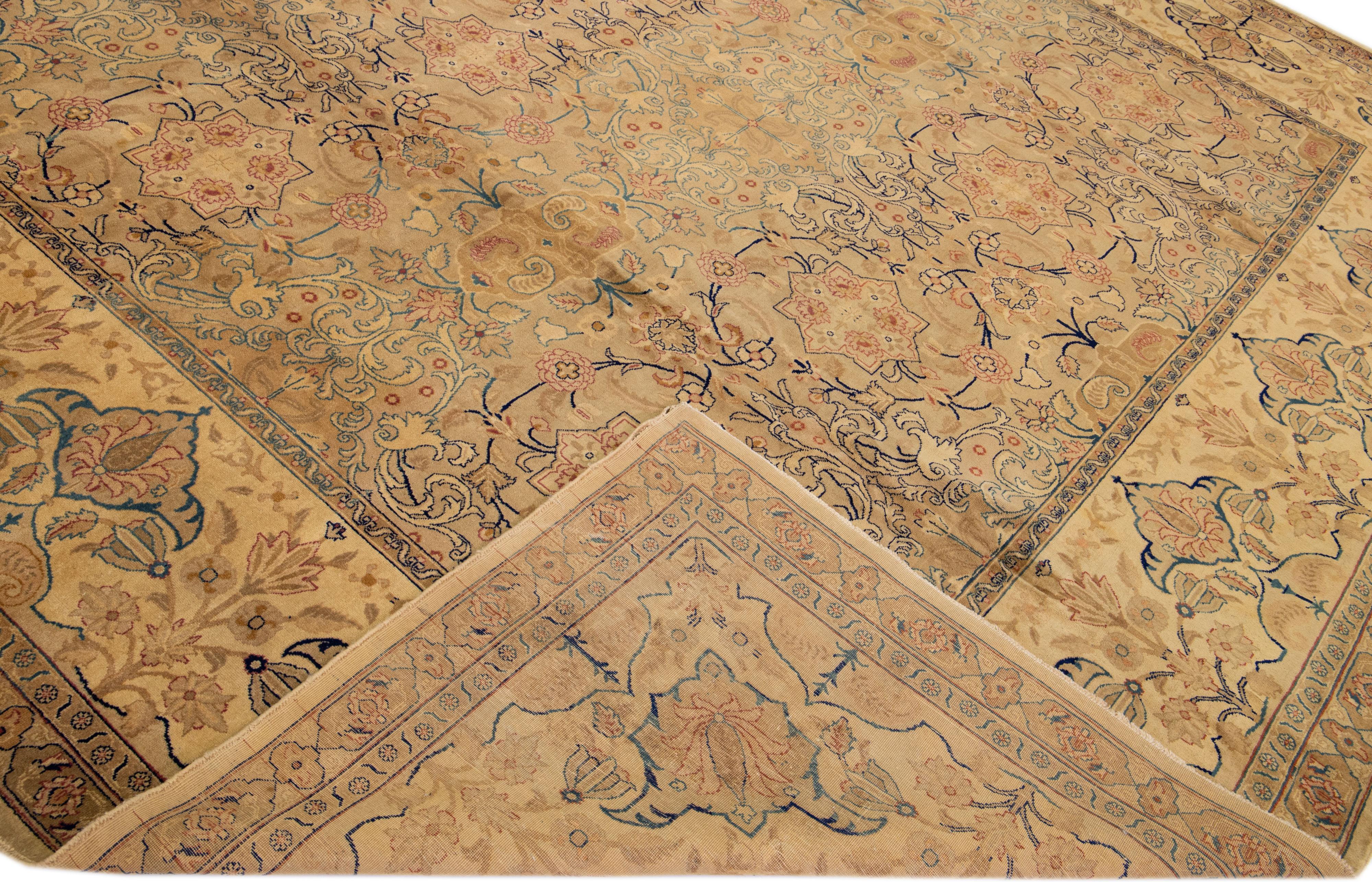 Beautiful antique Tabriz hand-knotted wool rug with a tan field. This Persian piece has orange, blue, and brown accents in a gorgeous all-over rosette design. 

This rug measures: 12'8