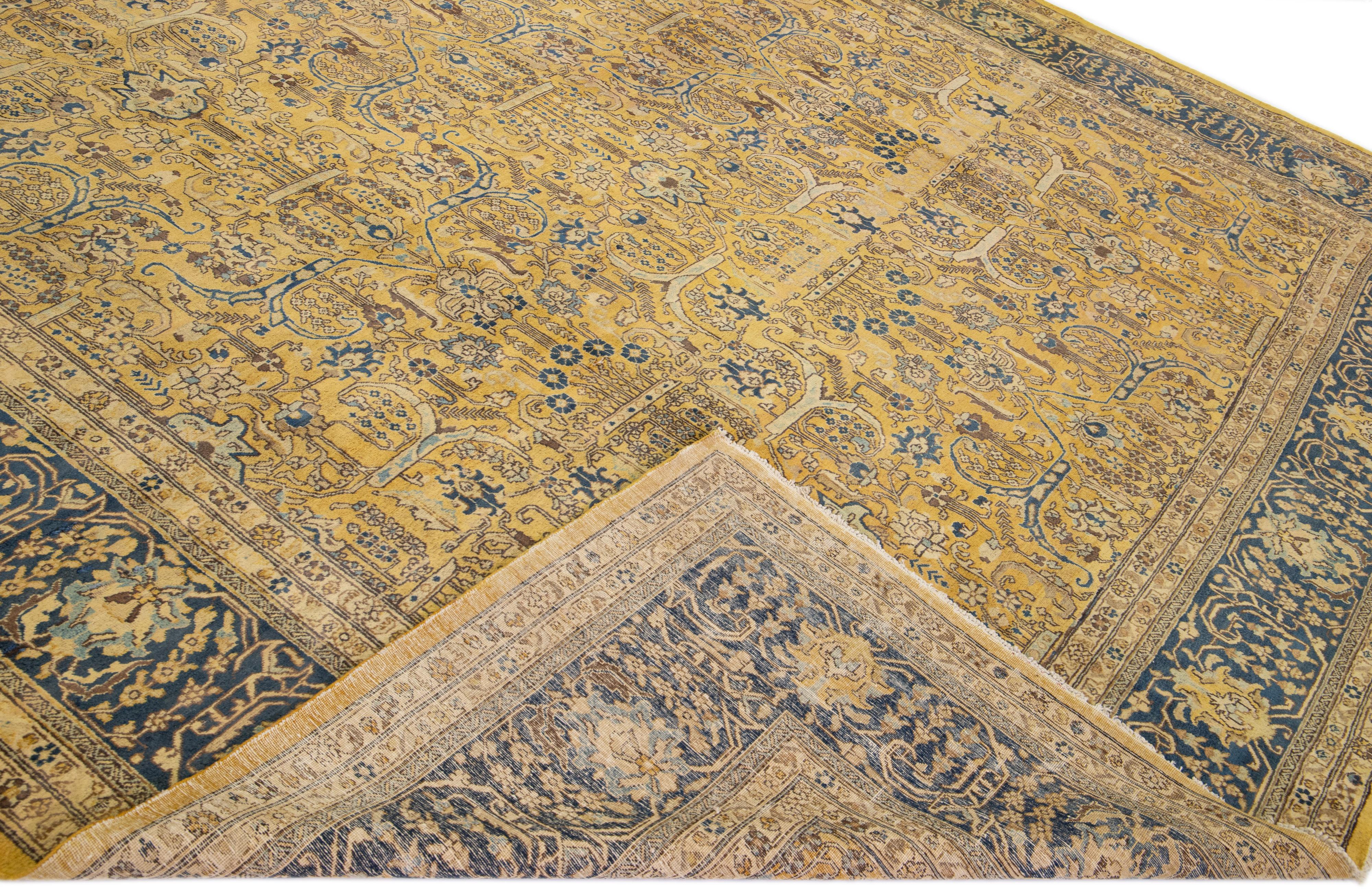 Beautiful antique Tabriz hand-knotted wool rug with a yellow field. This Persian piece has a blue frame and brown accents in a traditional floral design. 

This rug measures: 12' x 16'10