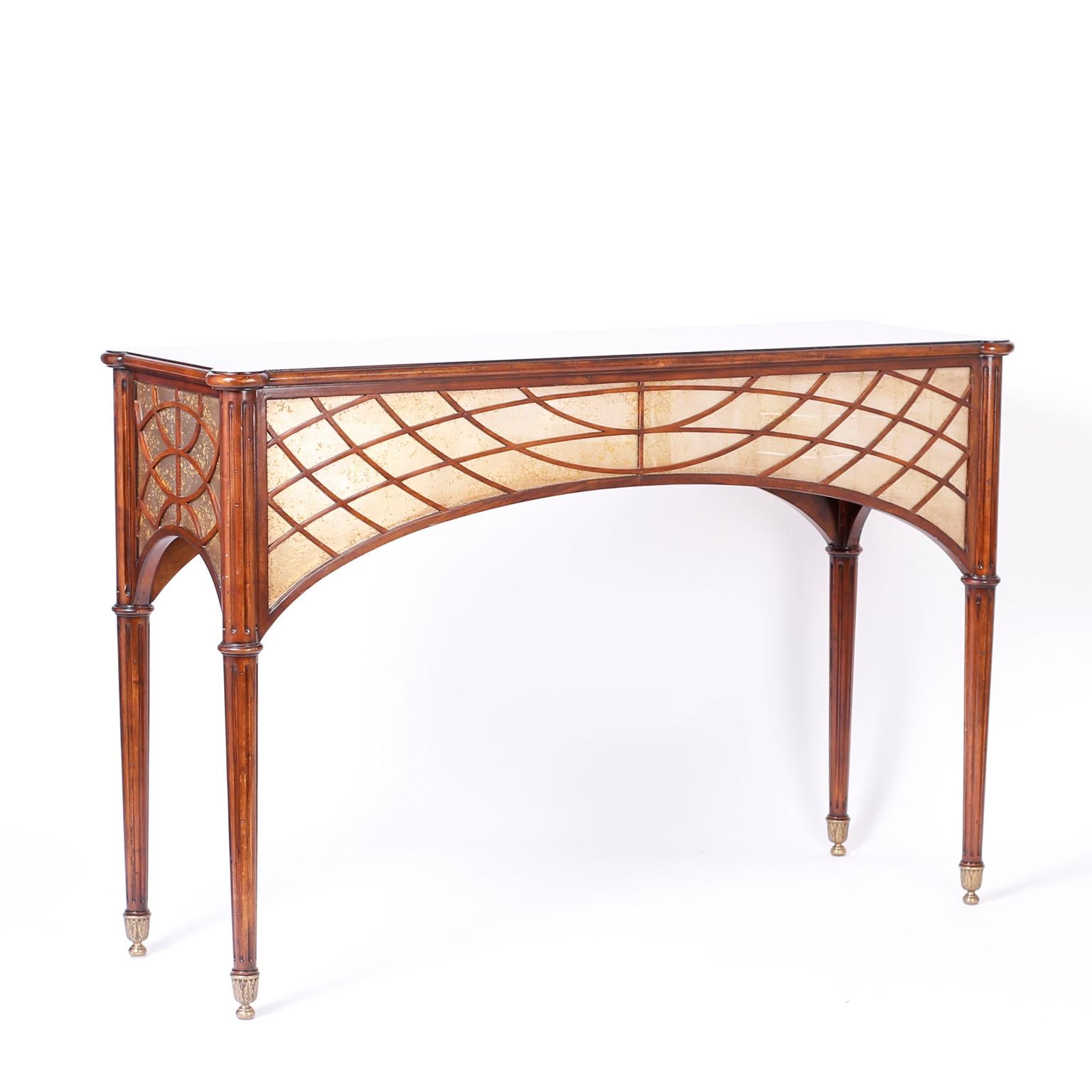 Rare and unusual antique English console table finished all around featuring a flame grained and crossbanded top over a distressed mirror and fretwork wood skirt. The long elegant legs are fluted and sit on cast brass feet with acanthus leaves.