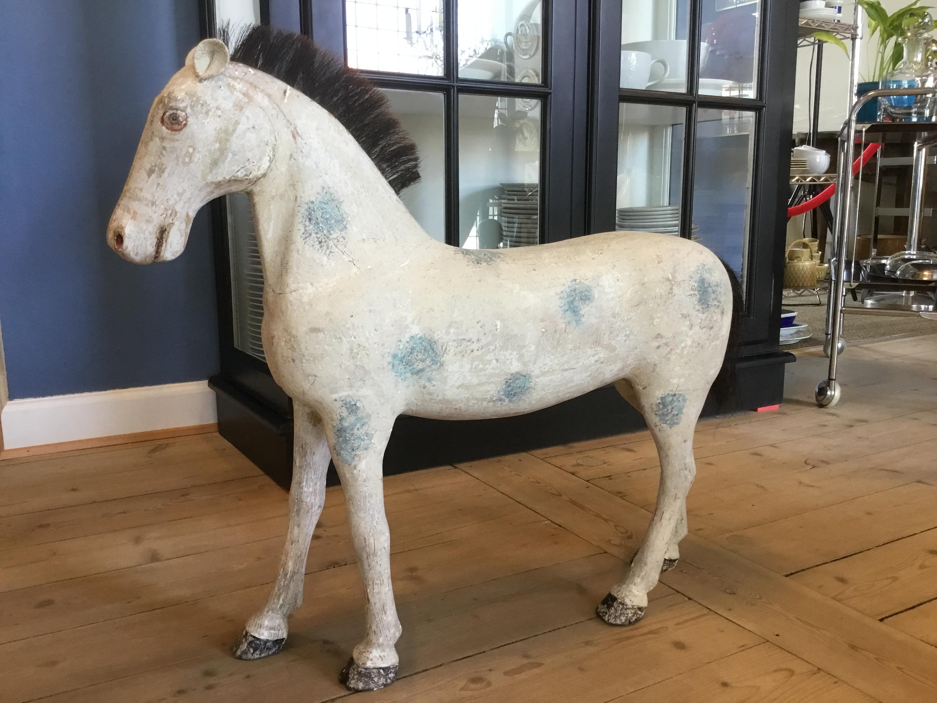 Grand cheval suédois ancien en bois sculpté avec peinture patinée d'origine de couleur blanc cassé avec des points bleus.
Fabriqué vers la fin du 19e siècle.
Les oreilles sont en cuir. La queue et la crinière sont en poils naturels.

Mesures : 
La