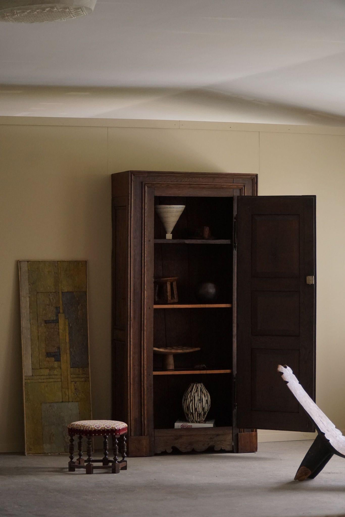This is a late 19th-century antique tall oak cabinet, crafted by a skilled French cabinetmaker. The cabinet features a sturdy, classic design typical of the period, with a rich oak finish that highlights the wood's natural grain. Inside, it contains