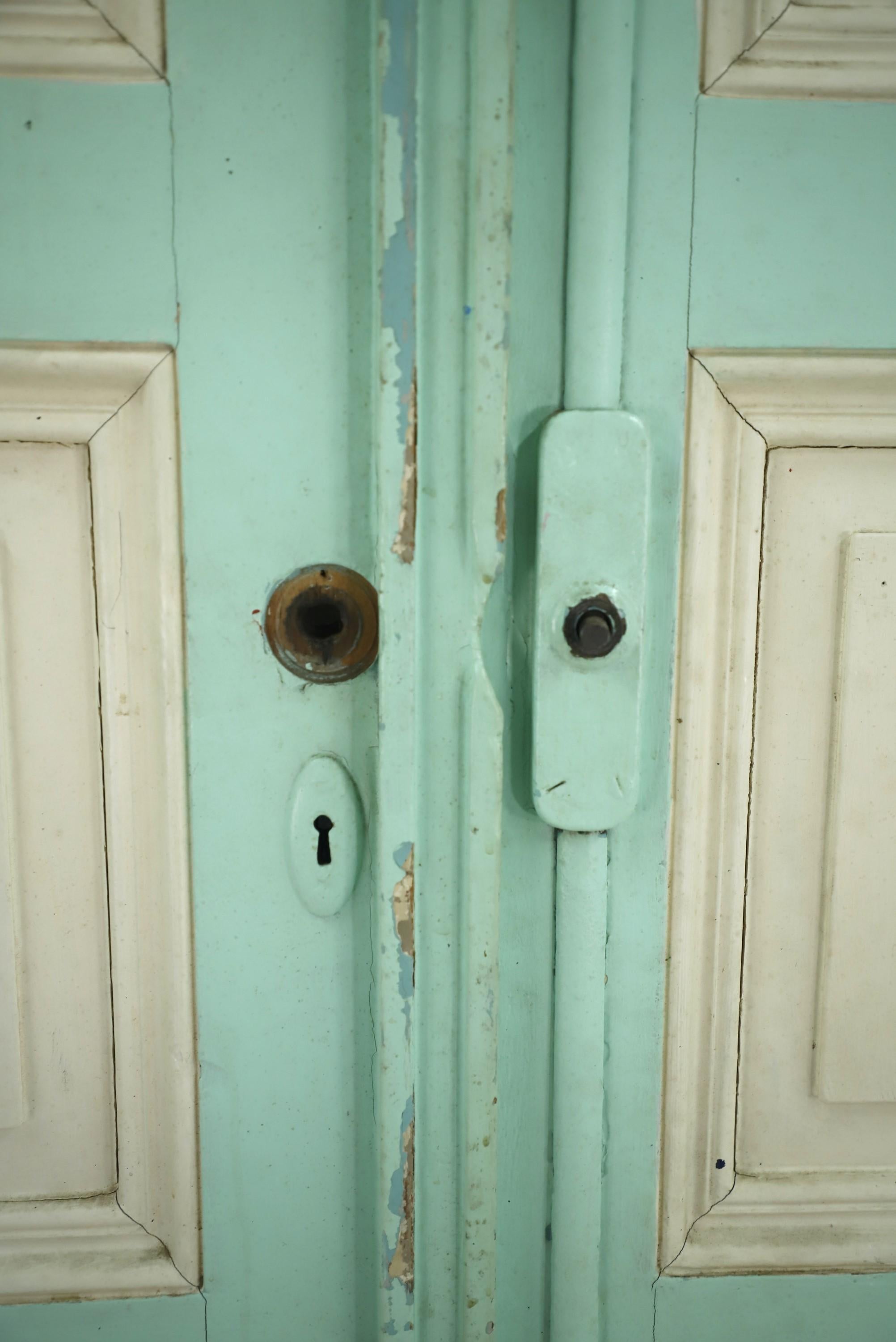 20th century pair of doors from an Argentina residence. Comes with the original teal paint. These wood doors feature three beige painted panels. Some minor chips in the wood and surface wear. Some original hardware included. Please see images.
