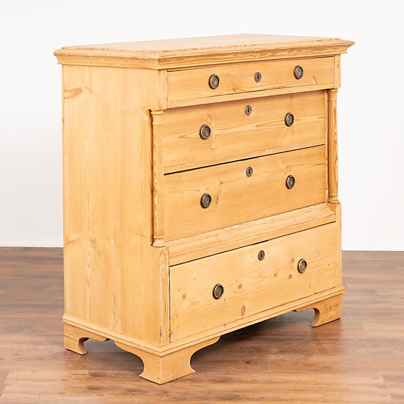 Antique 19th century Swedish pine highboy chest of four drawers. Notice how the upper and lower drawers sits forward of the two central drawers that are accented by long turned columns. There are two brass pulls on each drawer which all function.