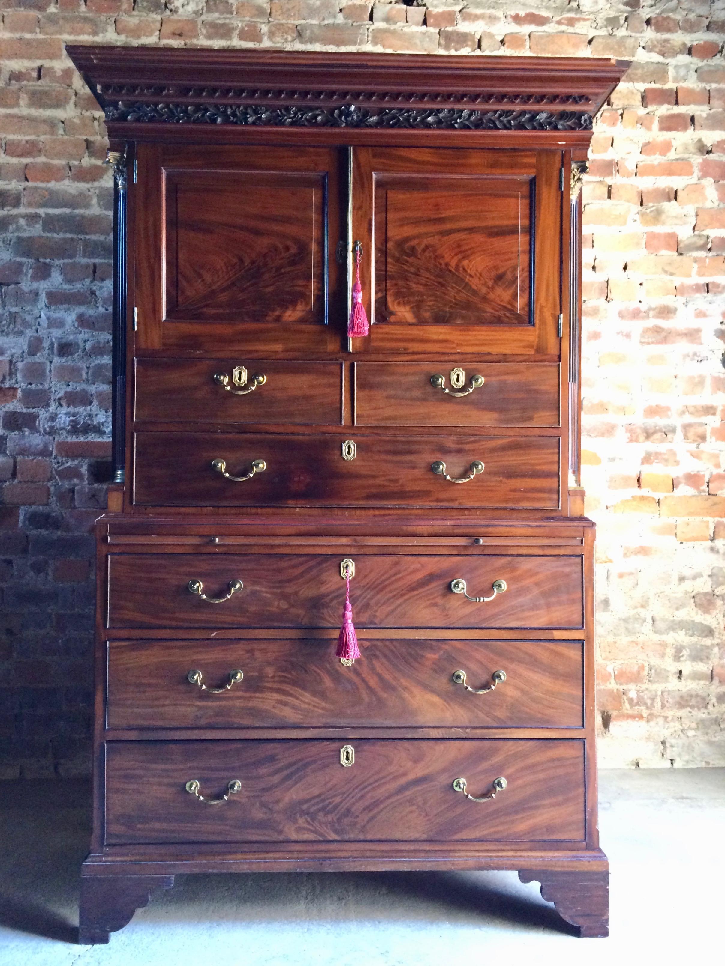 A magnificent George III inlaid flame fronted mahogany tallboy chest on chest, circa 1810, the ornate overhanging moulded cornice above a pair of short cupboard doors, above two short and one long drawer over a pull-out brushing slide, flanked