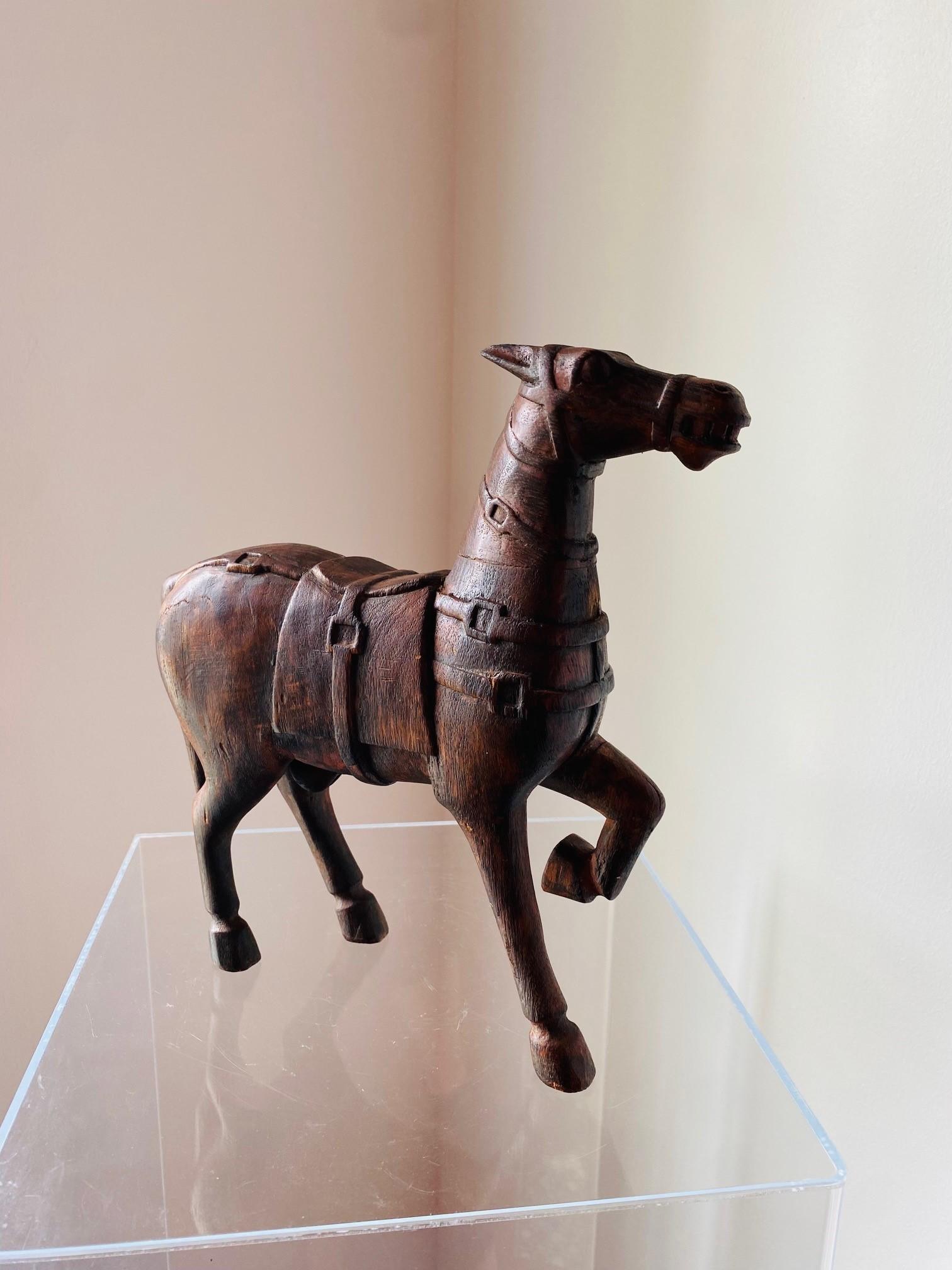 Das wunderschön handgeschnitzte chinesische Holzpferd ist im Stil der Pferde aus der Tang-Dynastie gehalten. Das MATERIAL ist ein dunkles Holz mit Resten von roter Farbe. Teile wurden separat geschnitzt und dann angebracht, wie z. B. das erhöhte