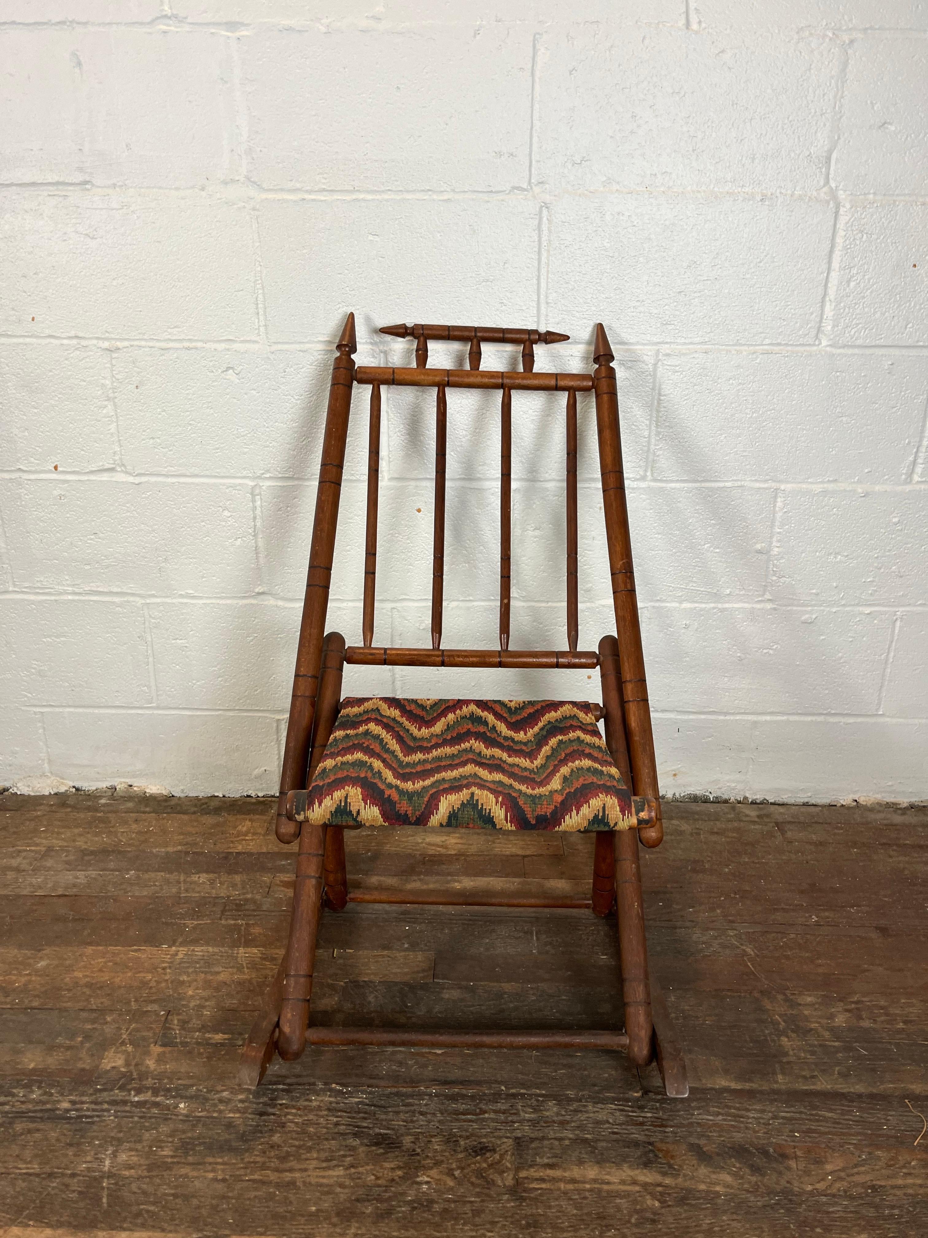 Vintage folding campaign or camp rocking chair. Eastlake style detail with finial tops. Nice flame stitch upholstery. Folds up for ease of transport and storage.