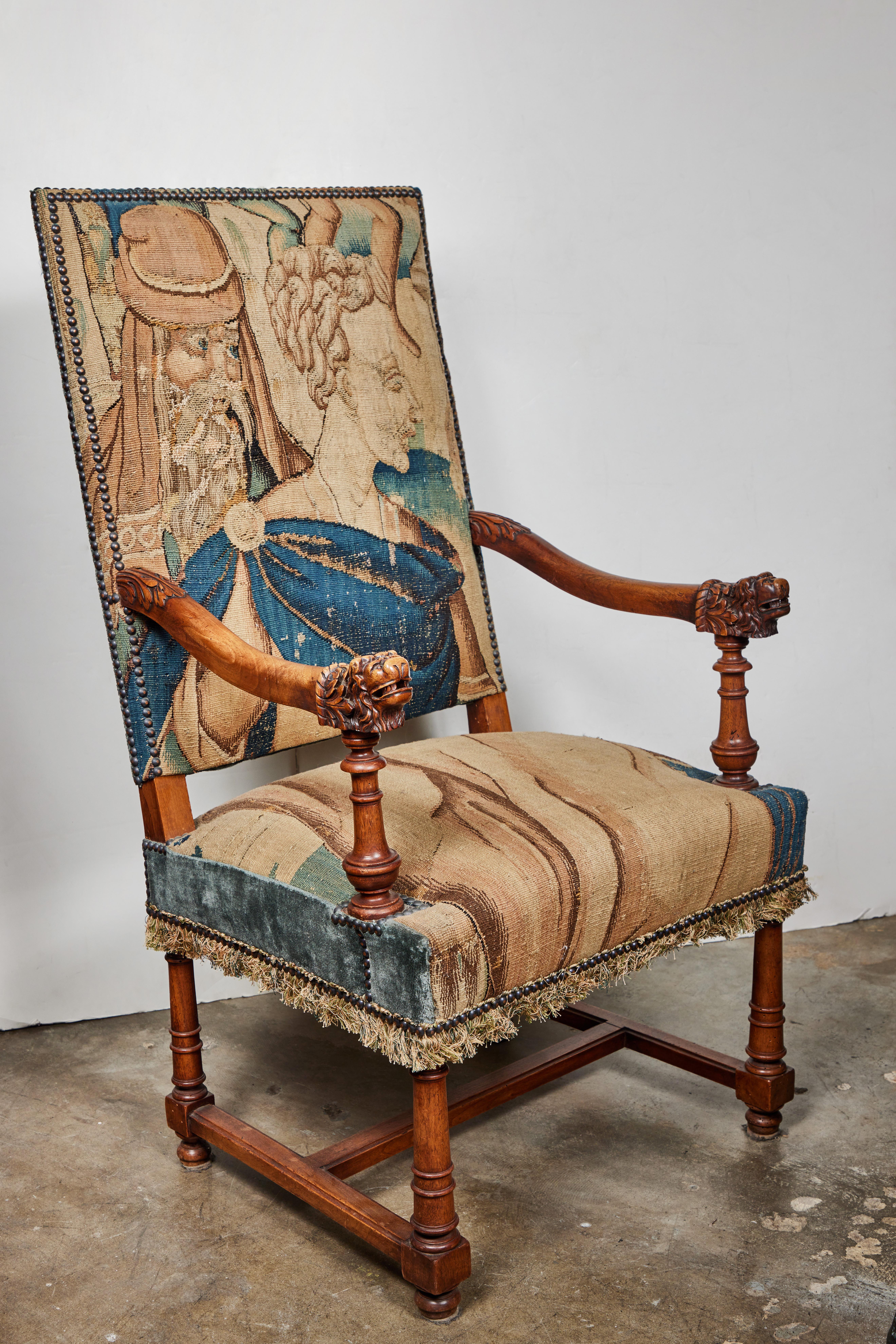 A beautiful pair of hand-carved, 19th c., French chairs with turned legs and arms terminating in lion heads. Each covered in 18th c., Flemish tapestry fabric and lined with bronze nail heads.
