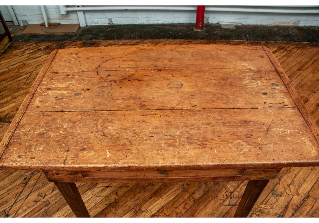 A Primitive Work Table with plank construction on the overhanging bread board edge top with separate carved and attached side ends. A single tool drawer and raised on square tapering legs. 
Measures: L. 48
