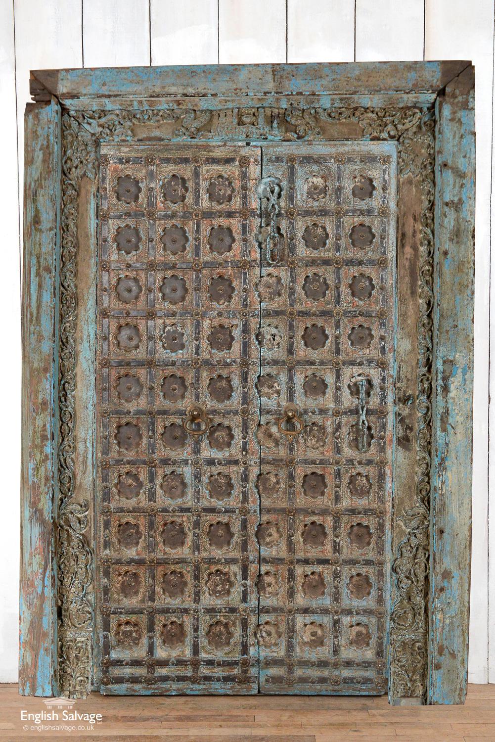 Stunning and unusual pair of antique Indian Jali doors in frame. Overall frame dimensions are given below and doors measure 102cm wide x 190cm high. The doors have ornate heavy brass knockers and brass studs as the centres of the floral motifs. Old