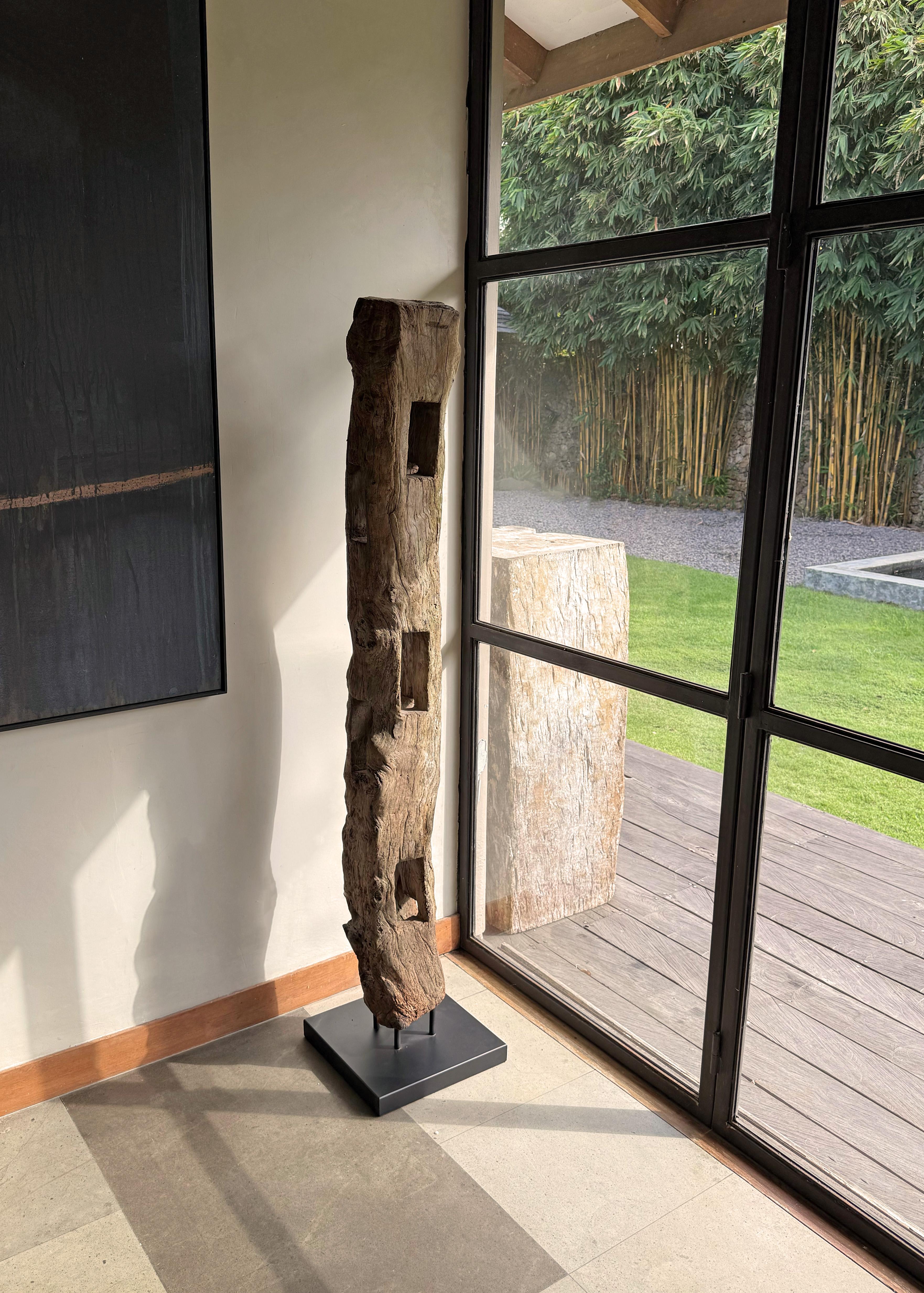 This striking artifact is an antique teak fence column from Java, Indonesia, once part of a traditional cow pen enclosure. Hand-hewn from dense, old-growth teak wood, the column now stands as a sculptural relic of rural craftsmanship and utilitarian