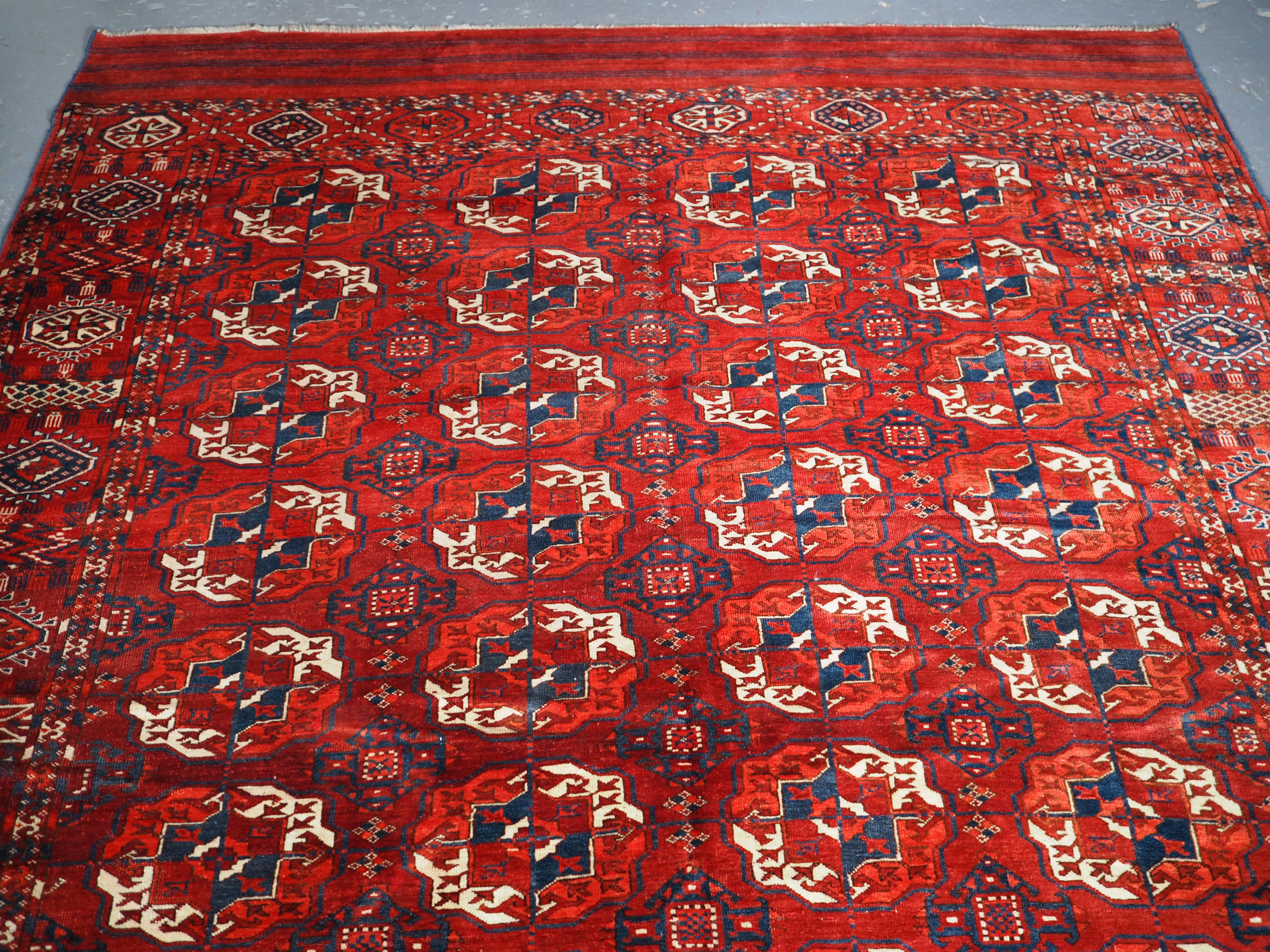 An excellent Tekke Turkmen main carpet of small room size. The clear madder red field has well drawn large round Tekke guls. The border is of the sunburst and octogen design. Note the piled elem panels at each end with a simple stripe design.

The