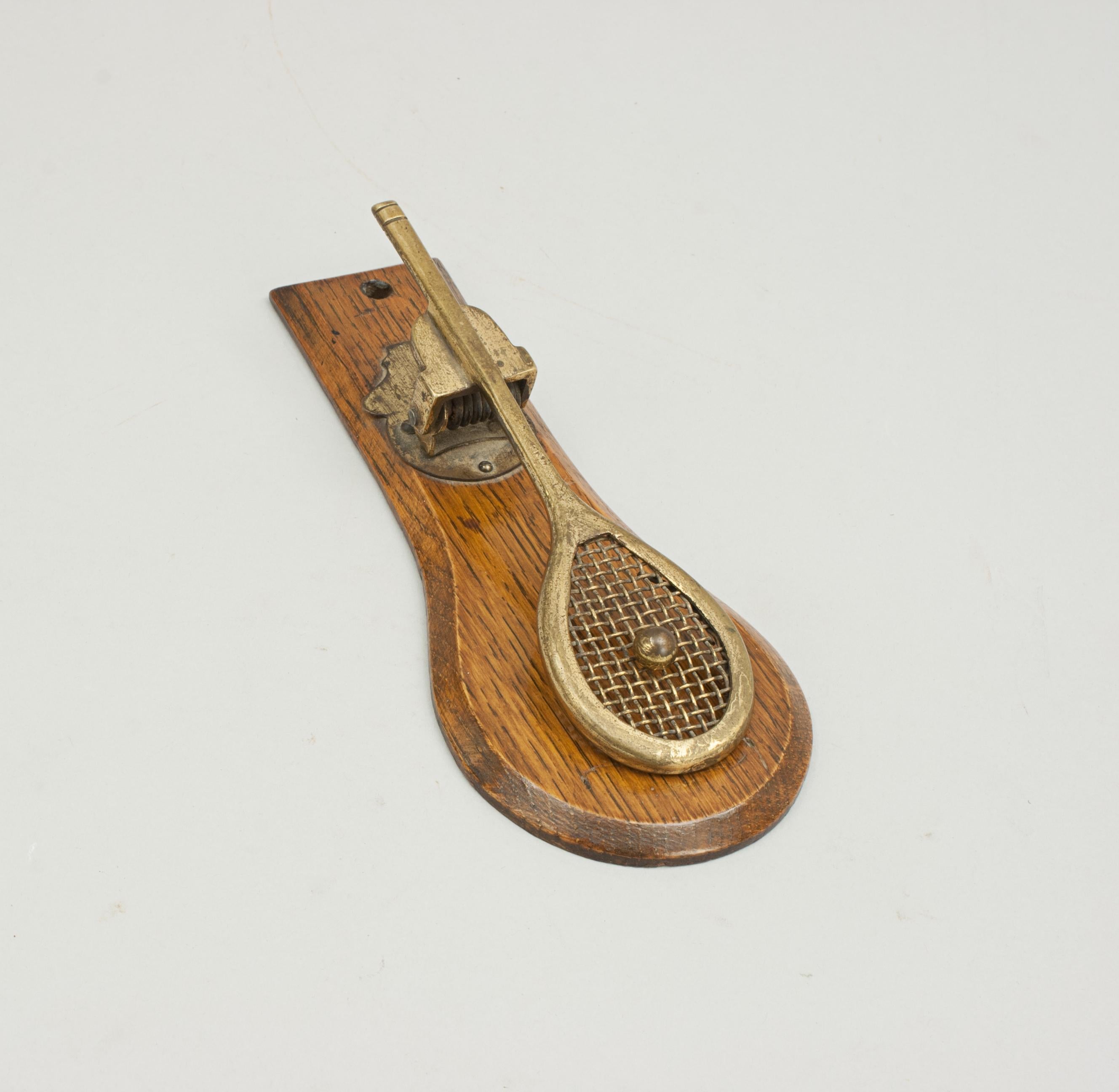 Vintage Oak & brass Tennis racket paper clip.
A good spring-loaded paper clip in the form of a tennis racket (with wire stringing). The brass racket is mounted onto a shaped oak back board.
A very nice tennis collectable desk