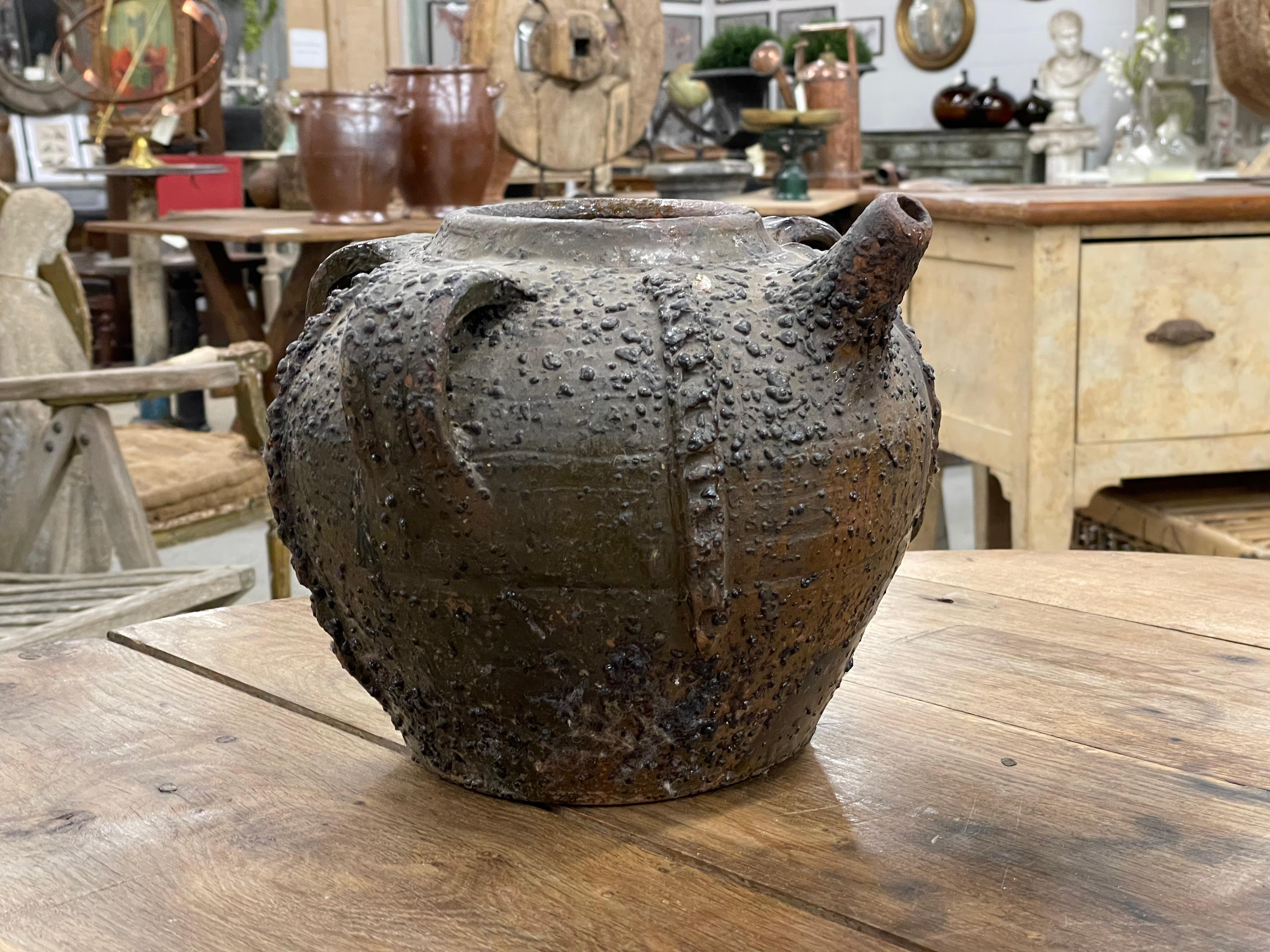 Lovely pot bellied glazed earthenware walnut oil jug with triple handles and spout is from the Périgord region in the Dordogne, France 

The jug was used to hold and transport walnut oil. Consequently, the body of the jug is covered with crystalized
