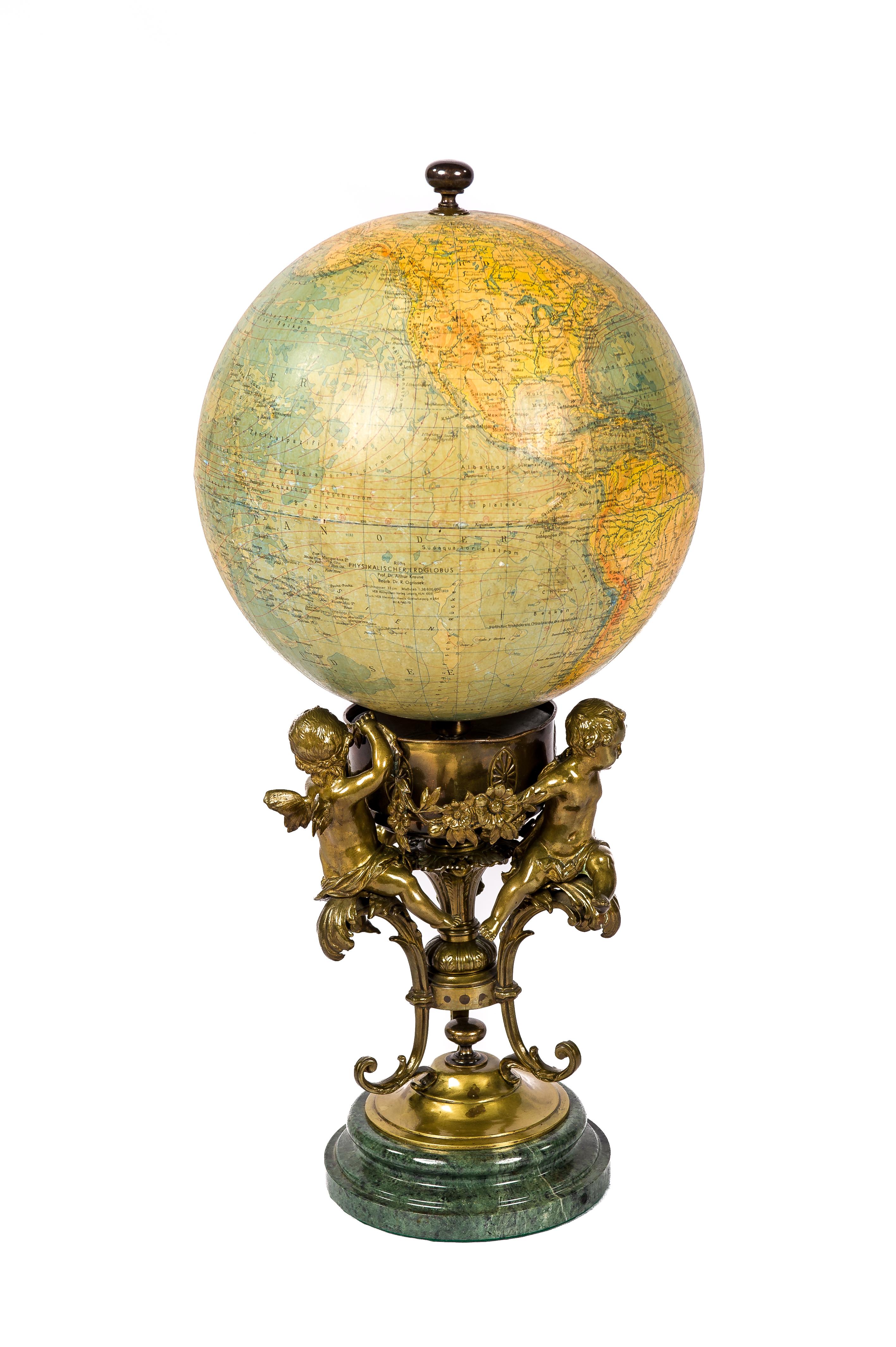 Globe terrestre ancien du professeur Dr Arthur Kraus, fabriqué par l'institut allemand Ráths. Le globe a une échelle de 1 : 38.600.900. Le globe repose sur une coupe en laiton décorée de trois chérubins ou anges en laiton patiné tenant une guirlande