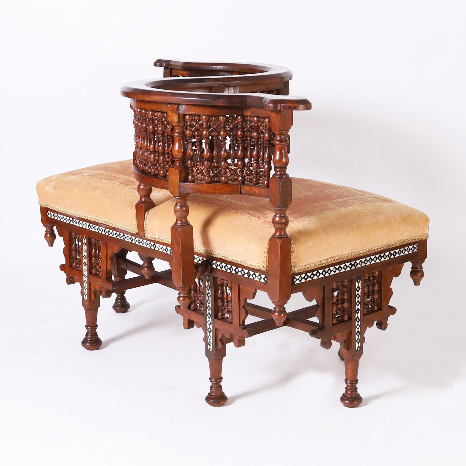 Rare and remarkable antique Moroccan tete-a-tete crafted in walnut in classic graceful form featuring geometric bone inlays, turned balustrades, stick and ball, custom floral upholstery, finials, and turned feet.