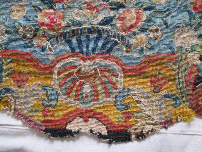 Antique textile blue floral square fragment with red garlands
Scattered flowers coming out of a vase at the center bottom of the antique textile.
In shades of blue, red, tan, green and pink. Red garlands on the top frame the scenery.
No repairs
