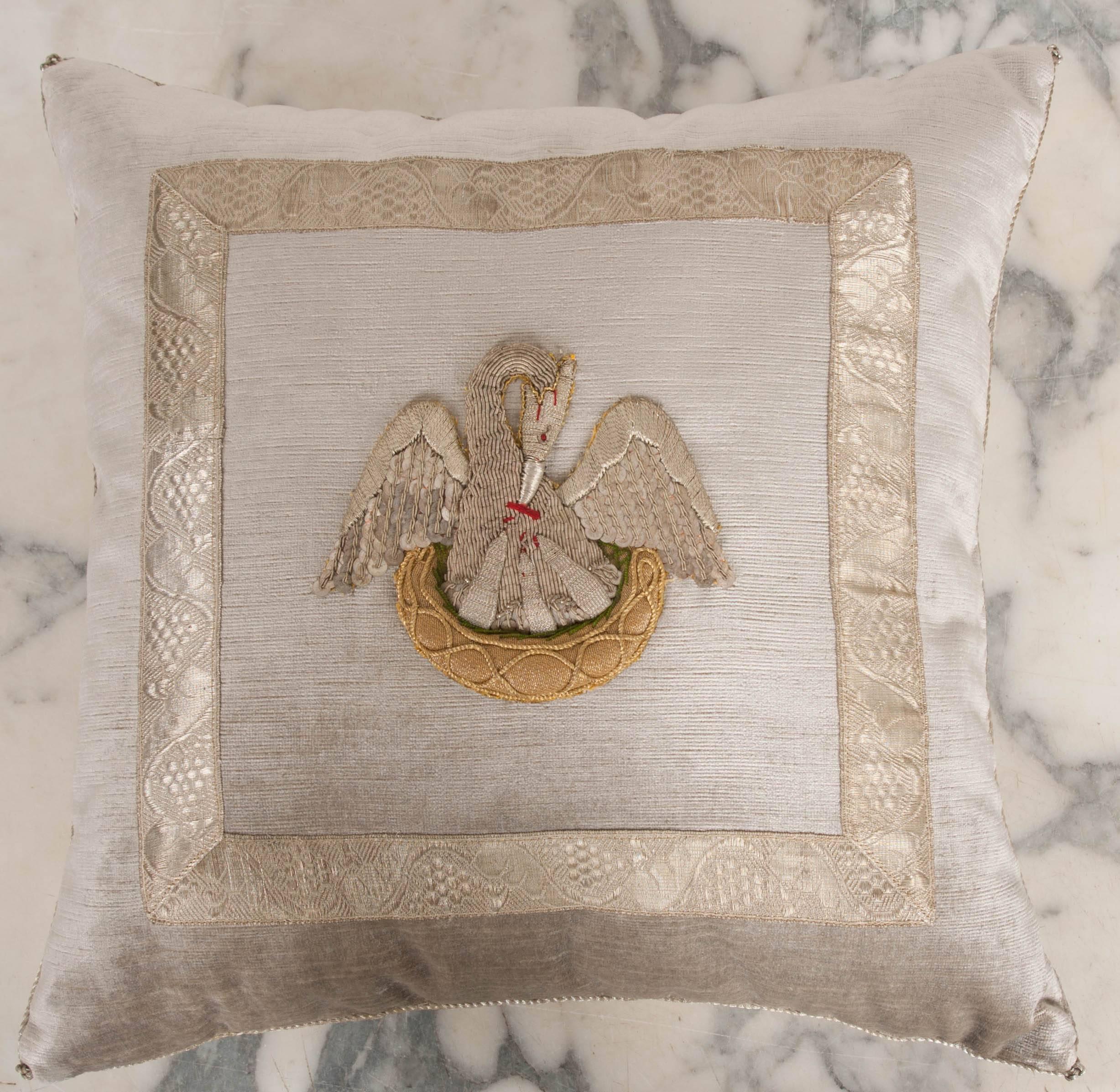 Antique Ecclesiastical silver and gold embroidered applique of The Pelican in Her Piety framed with warm antique silver galon on silver velvet. Hand trimmed with vintage silver and gold cording knotted in the corners. Down filled.



