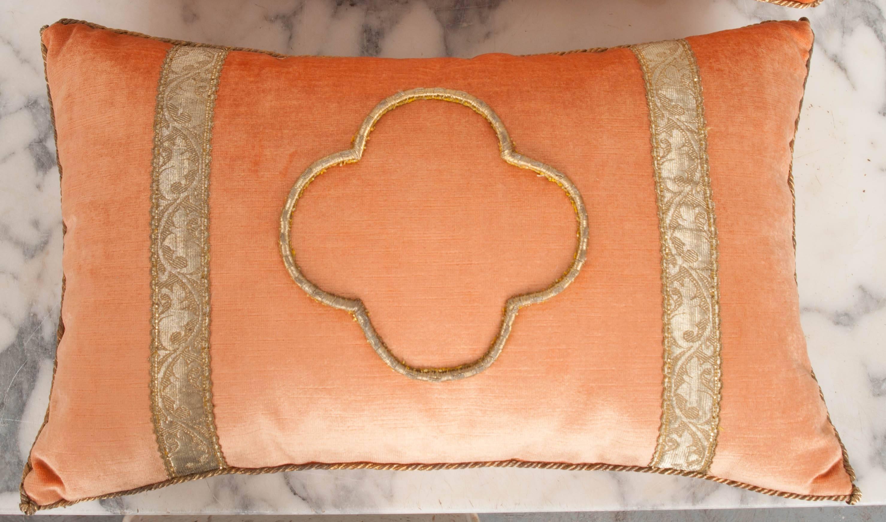 Antique European raised gold metallic embroidery of a quatrefoil bordered with antique gold metallic gallon on melon velvet. Hand-trimmed with vintage gold metallic cording knotted in the corners. Down filled. Available for individual purchase: