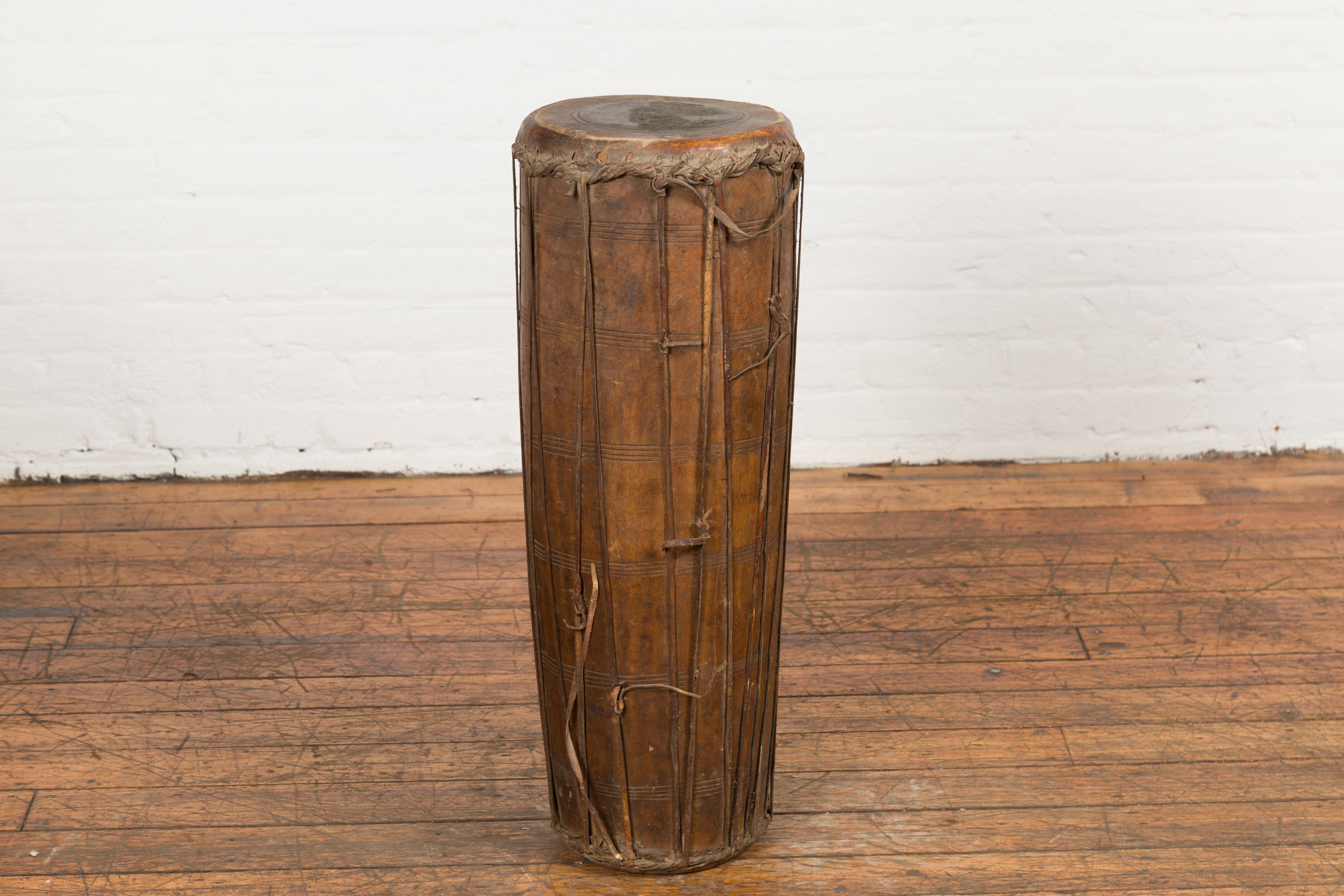 An antique Thai wood and leather Klong Khaek processional drum from the 19th Century, with ties and weathered patina. Created in Thailand during the 19th century, this Klong Khaek drum was likely used in Thai ensembles for processions. The