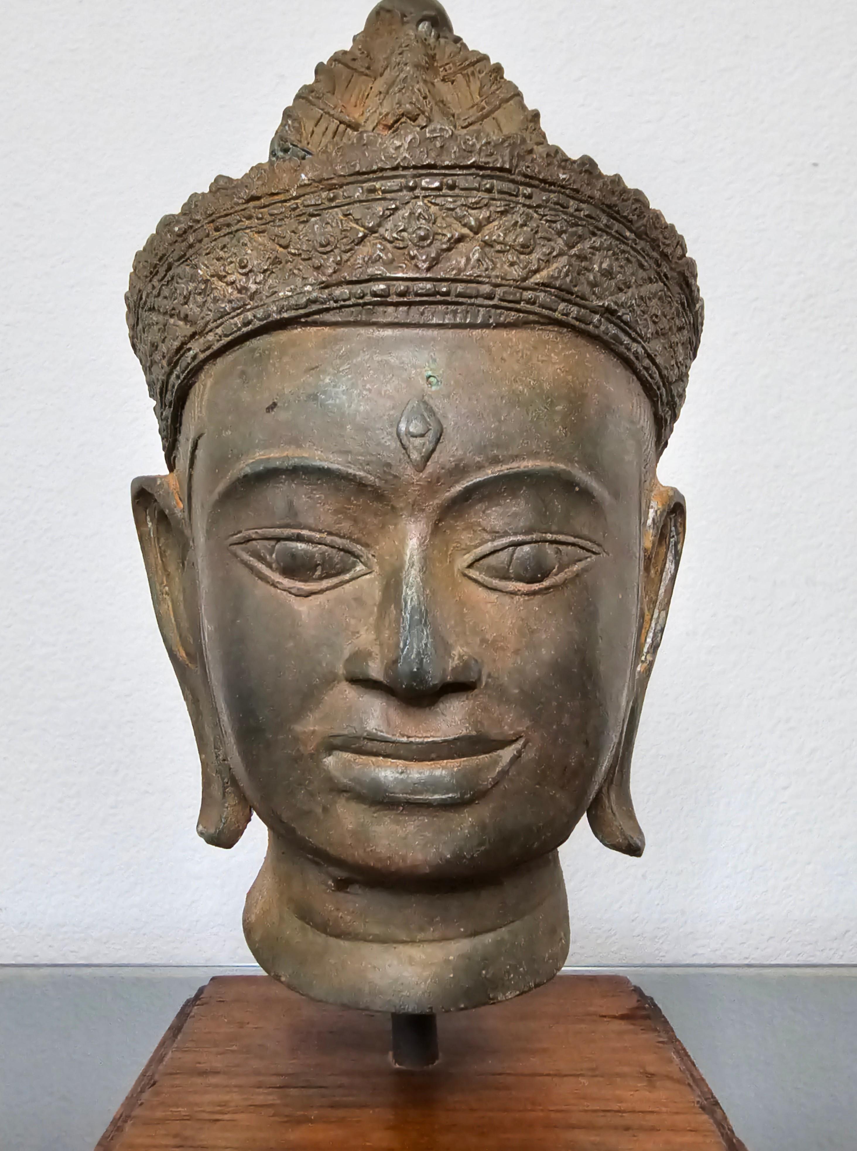A finely detailed antique Southeast Asian bronze Buddha head, 18th/19th century or possibly older, Siam/Thailand, exceptional quality bronze work, mounted on a later wooden display stand. 

Dimensions: (approx)
Overall: 11.5