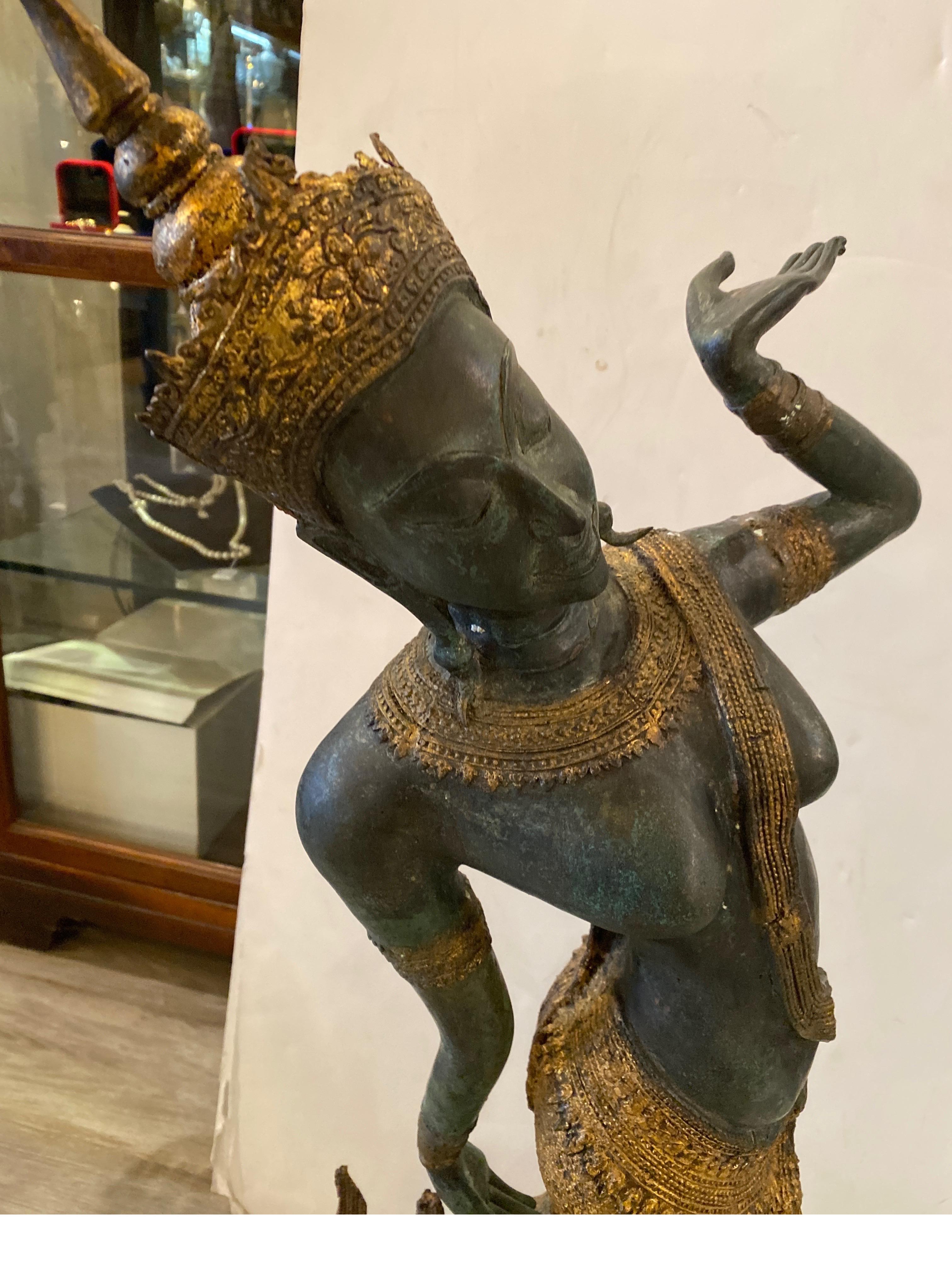 An antique bronze figure of a Thai dancer. The patinated and gilt bronze surface, all original. In very good condition with original aged finish. The female dancer with traditional costume with graceful pose. The rectangular base with a dark