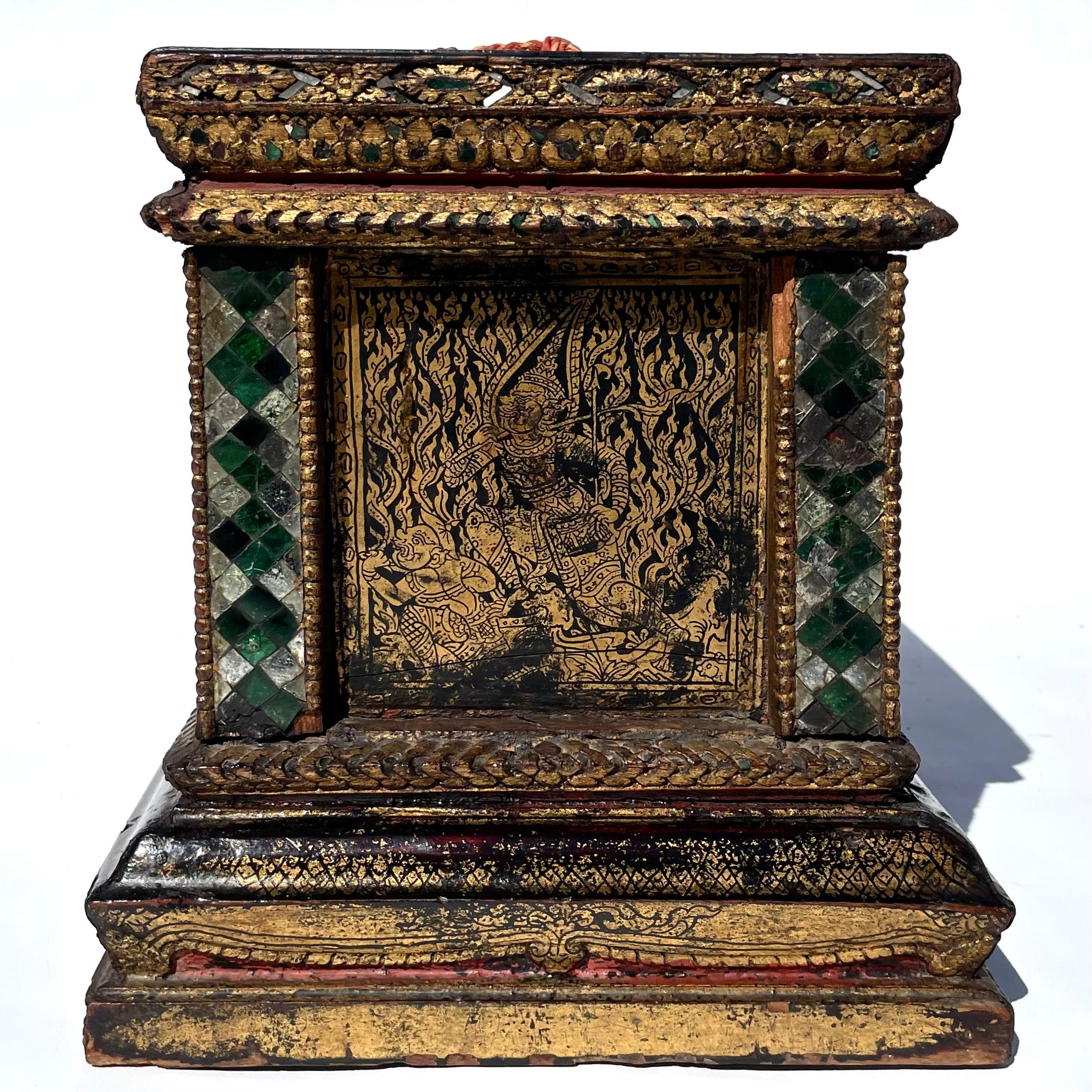 Constructed of Teak with carved stepped base, 8 inset side panels decorated in the Lai Rot Nam tradition of black lacquering and etched gold leaf creating an intricate foliate tendril background with celestial imagery and duels, possibly from the