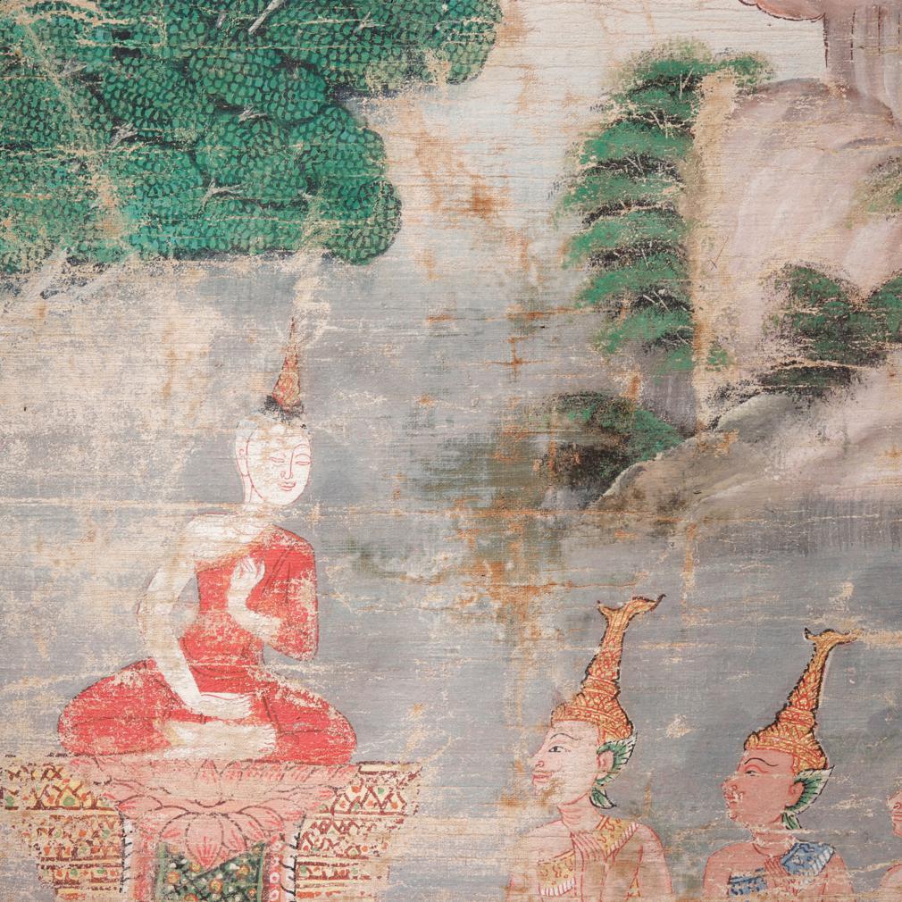 Thai Buddhist painting on cloth of  a red cloaked monk on a raised pedestal underneath a tree giving a sermon to five crowned, kneeling and praying divinities, possibly a scene from the story of Phra Malai. 
Losses to pigments, water staining near