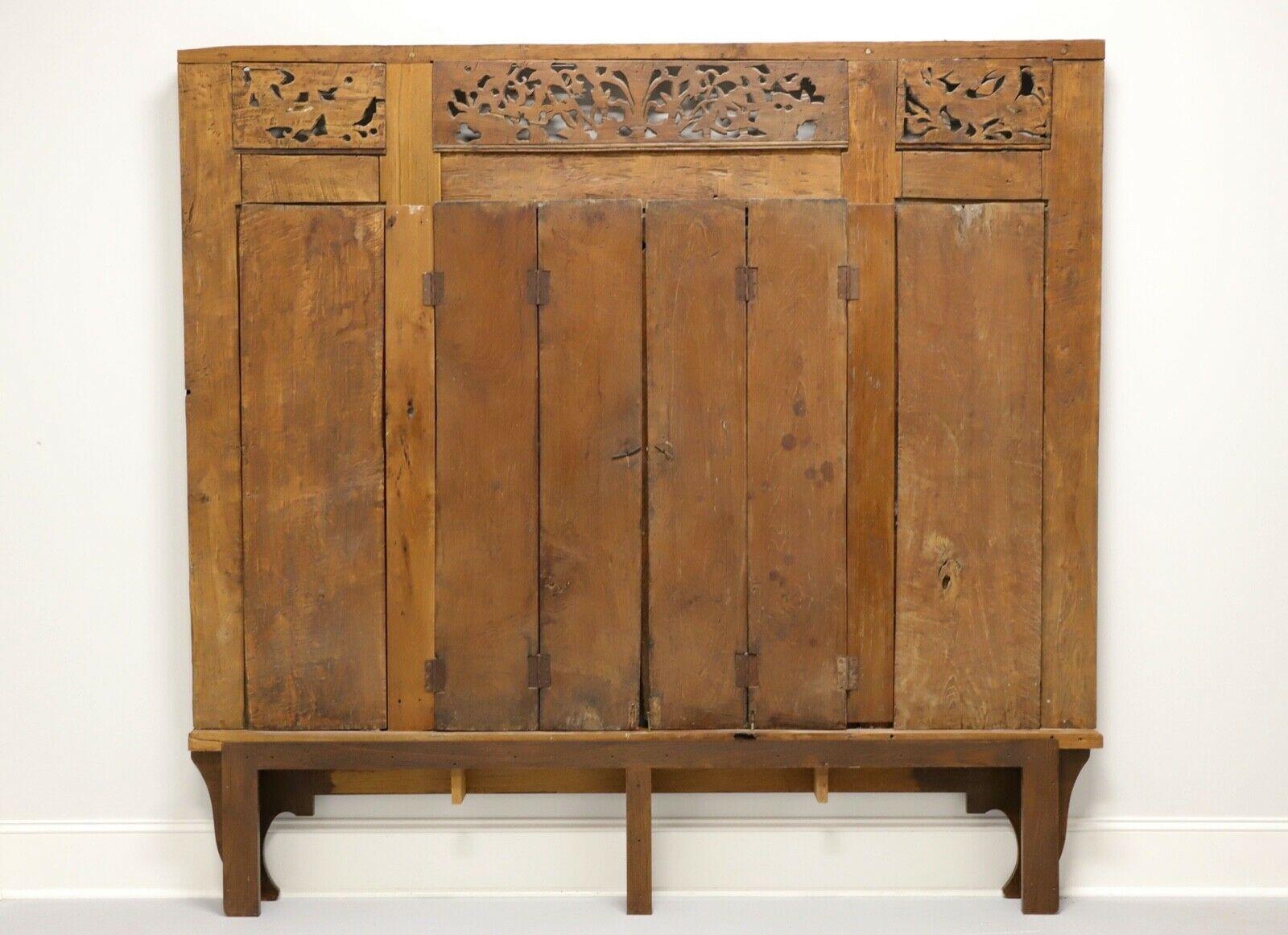 An antique Asian style Thai carved panel with doors and base, unbranded. Solid wood with intricately hand carved detail and center bi-fold doors with metal hardware. Made in Thailand in the late 19th Century. Could be used as king size headboard,
