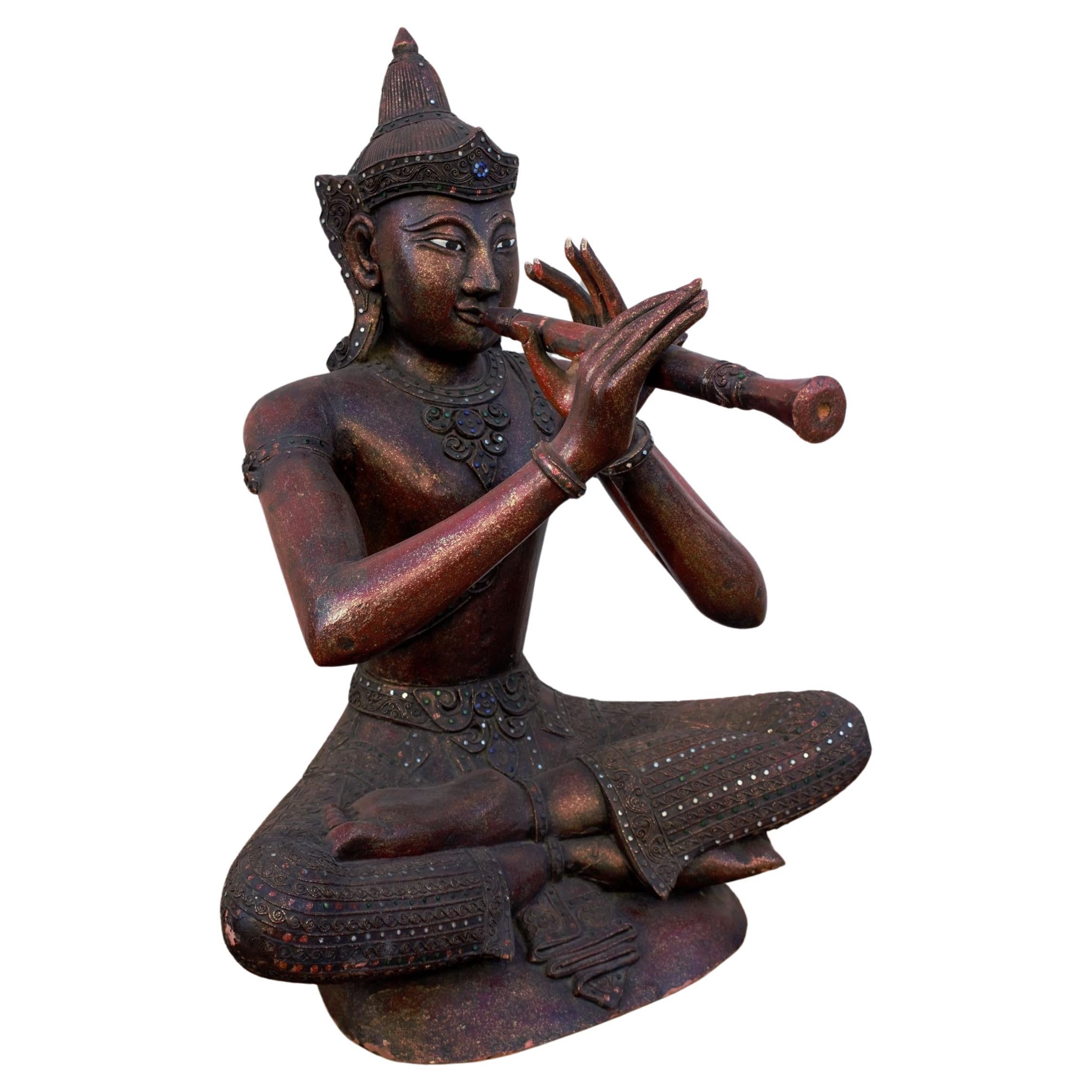 Antiker thailändischer geschnitzter sitzender Buddha, der eine Flöte spielt im Angebot