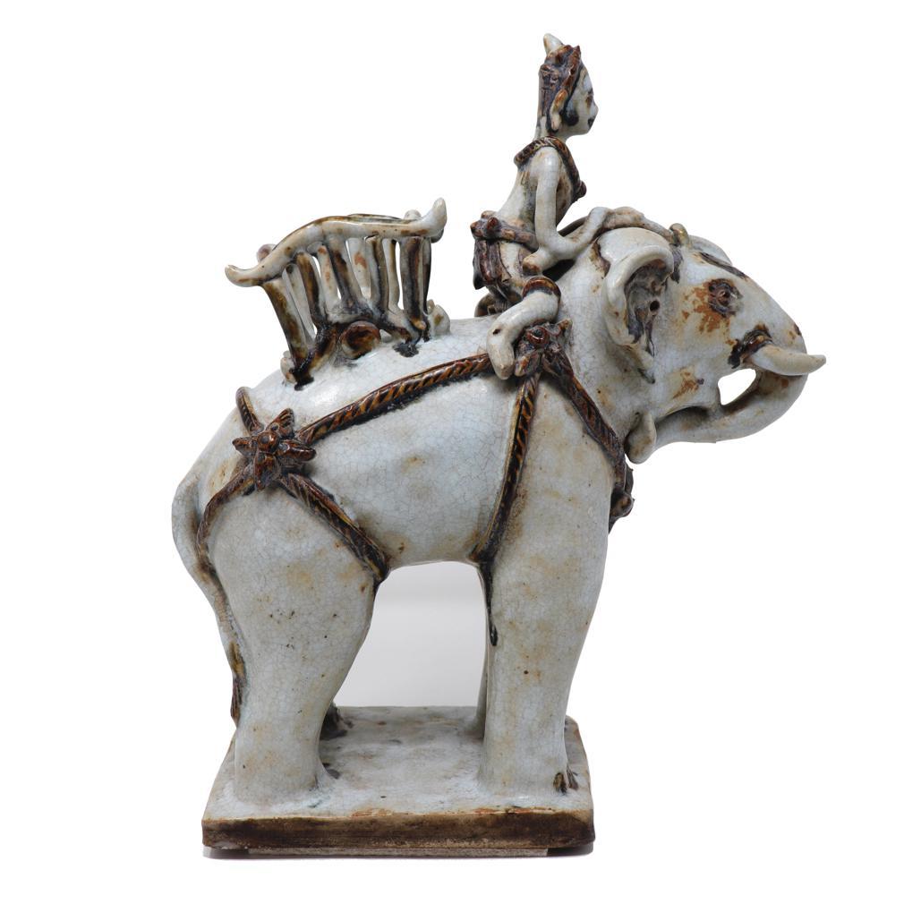 Antique Thai Ceramic White War Elephant. A hand sculpted stoneware figure of elephant and rider. The solid elephant stands firmly four square on a rectangular slab base. The head is pointed forward with the trunk tucked in beneath the chin and the