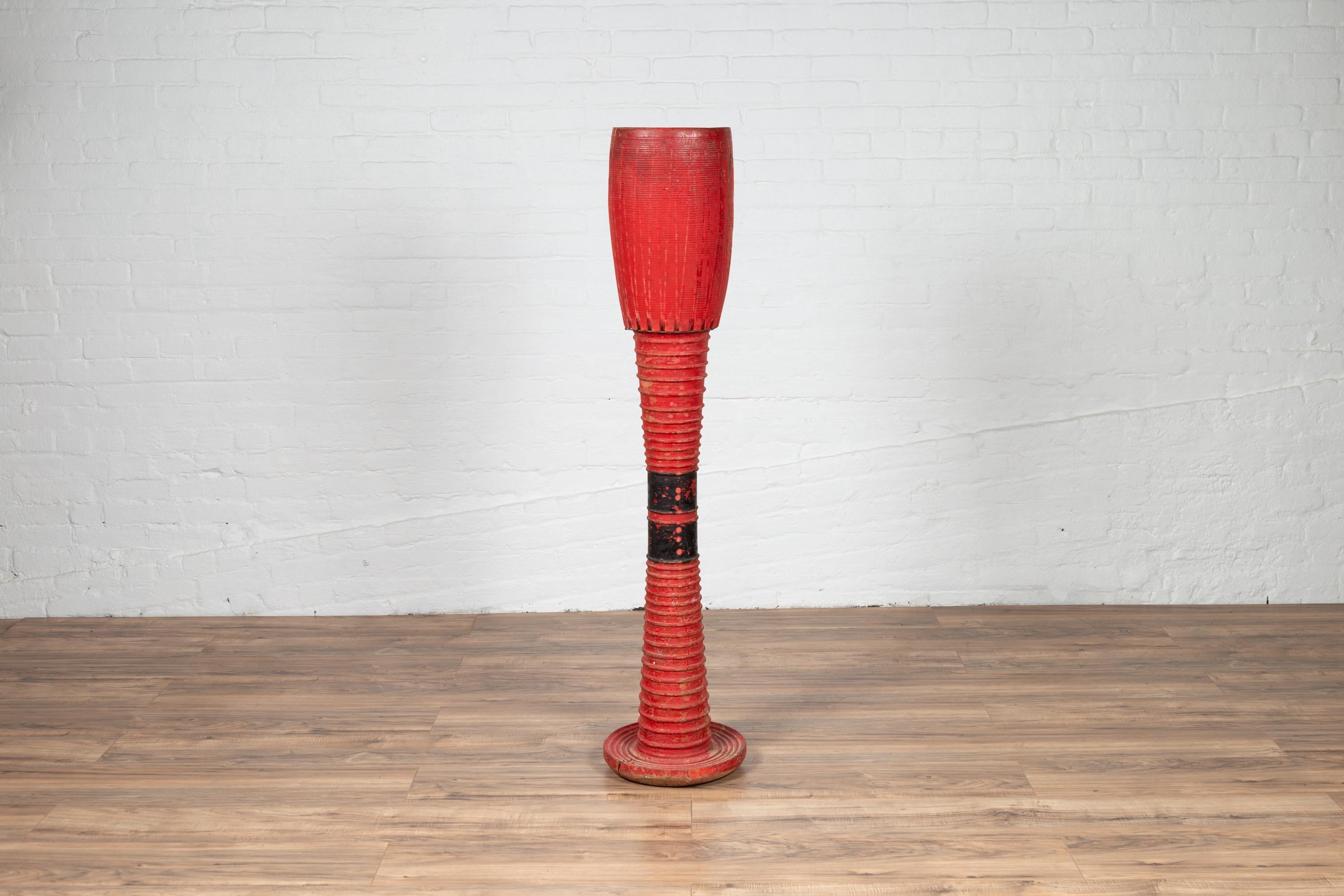A tall antique Thai freestanding ceremonial drum from the early 20th century, with red finish, reeded accents and circular base. This early 20th-century tall antique Thai ceremonial drum, standing with a commanding presence, offers a remarkable