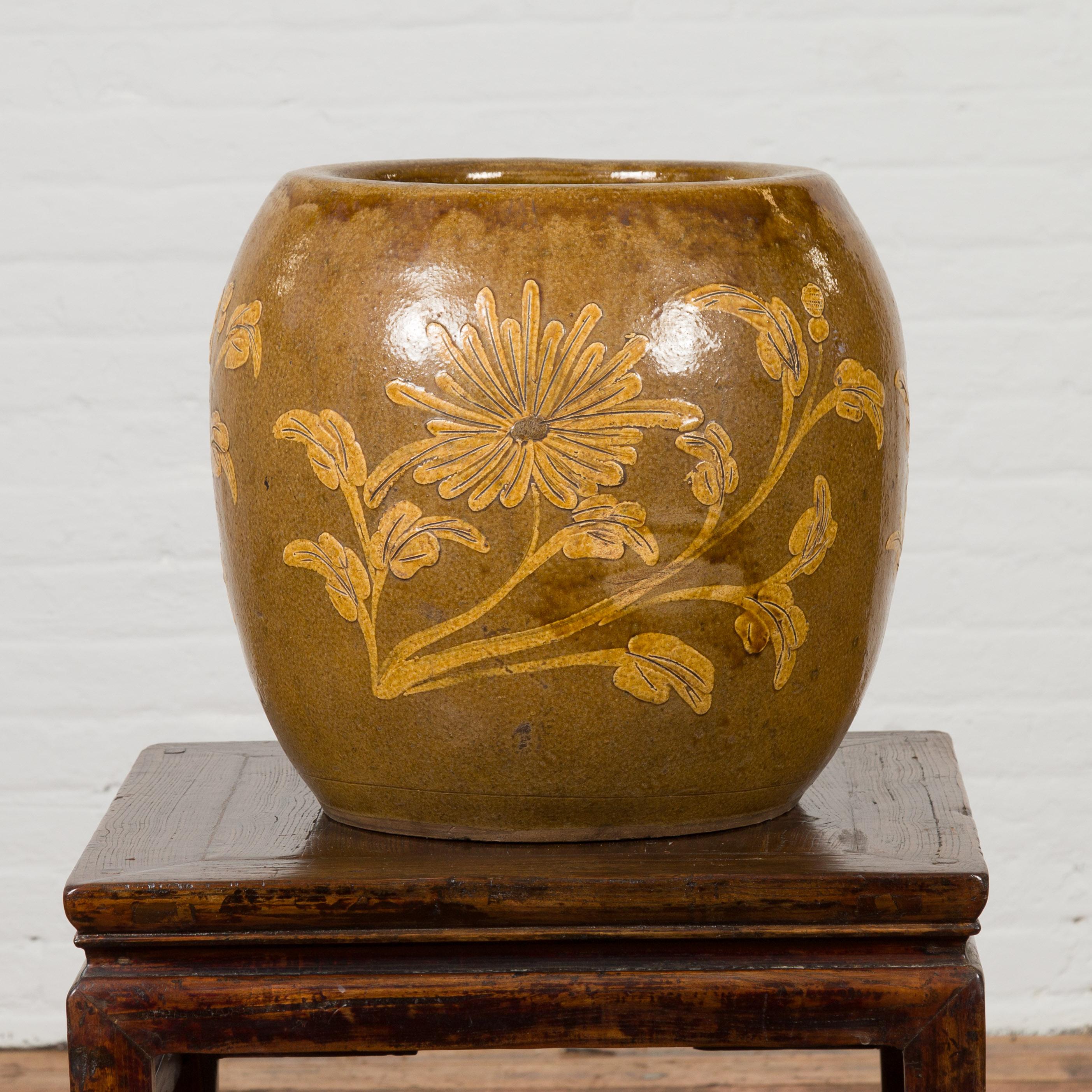 An antique Thai glazed ceramic planter from the 19th century, with floral motifs. Created in Thailand during the 19th century, this round planter showcases a brown ground accented with golden flowers on the belly. Glazed on the inside as well and