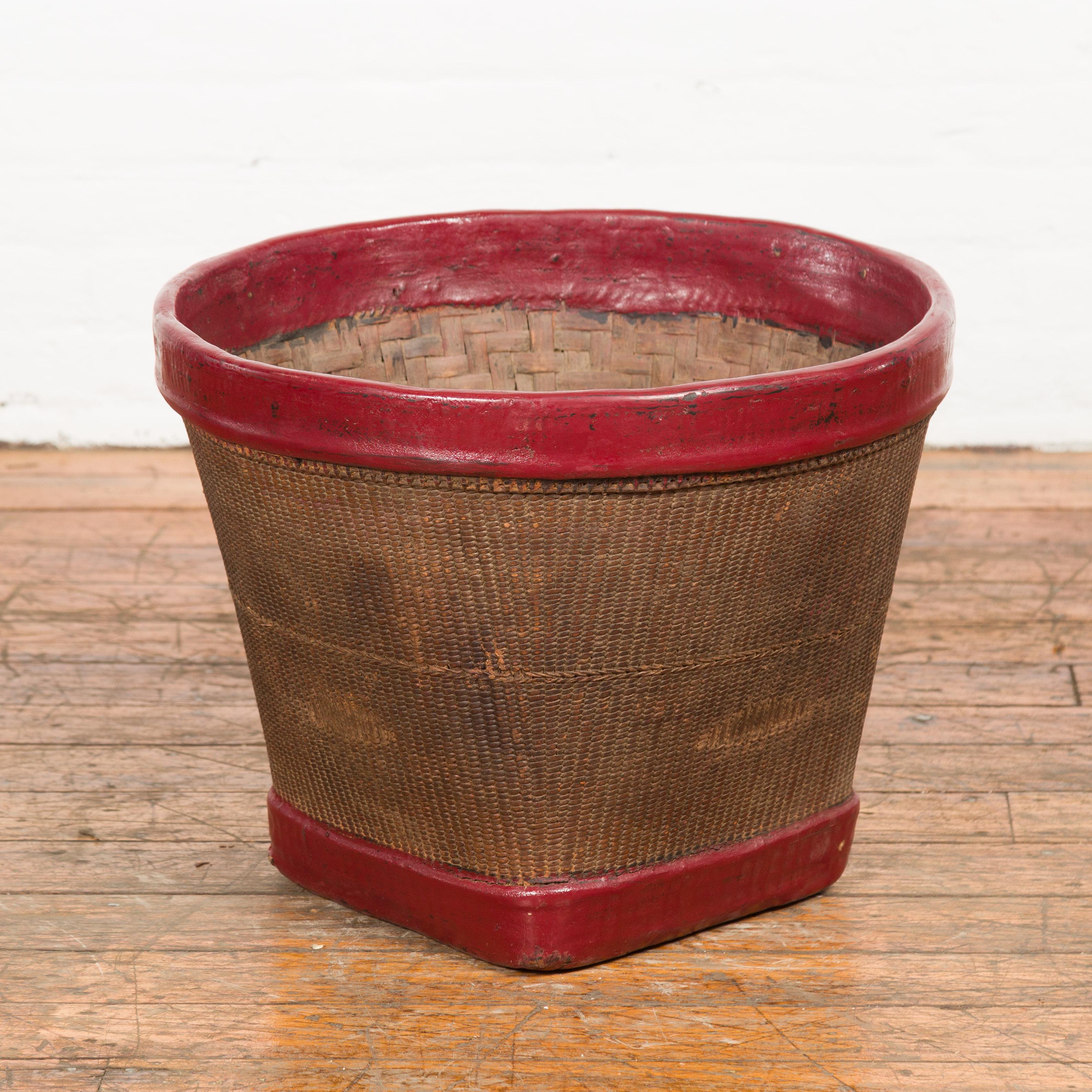 An antique Thai hand-woven rattan grain basket from the 19th century, with red lacquered rim, tapering lines and rustic character. Created in Thailand during the 19th century, this rice basket charms us with its rustic appeal and contrasting colors.