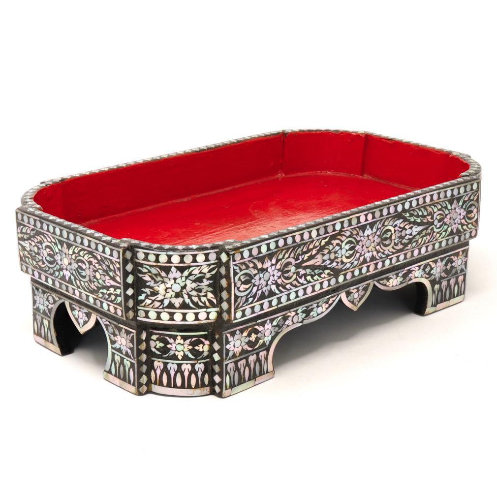 Antique Thai Mother-of-Pearl Inlaid Offering Tray. Crafted of assembled wood in an elevated and footed rectangular shape with rounded corners, lacquered red on the interior and black on the exterior, exquisitely decorated with a floral, flame and