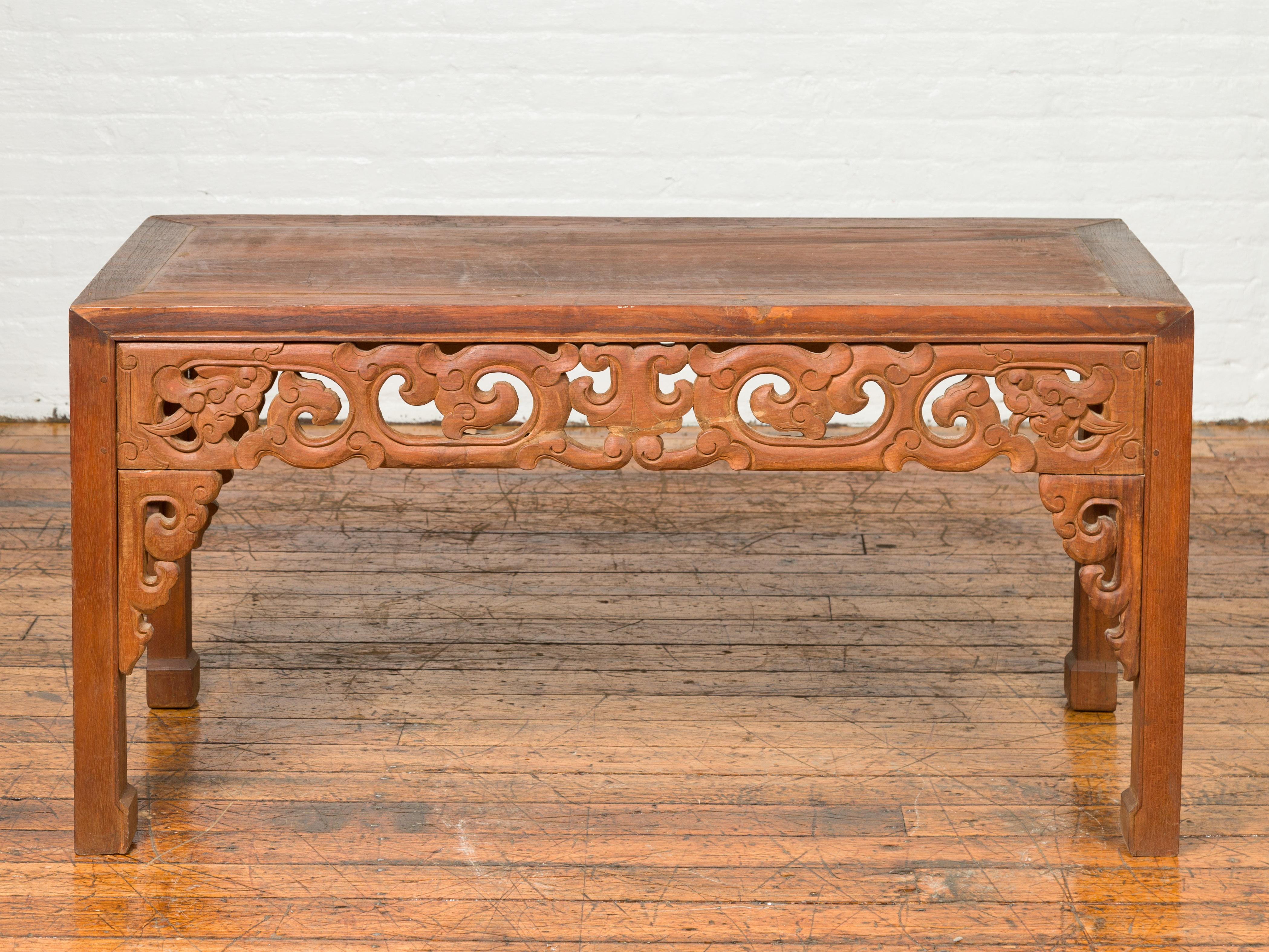 Table d'appoint ancienne en teck thaïlandais du début du 20e siècle, avec tablier sculpté et extrémités en sabots de cheval. Charmant nos yeux avec ses lignes épurées et son beau tablier sculpté de motifs de nuages en volutes, cette table d'appoint