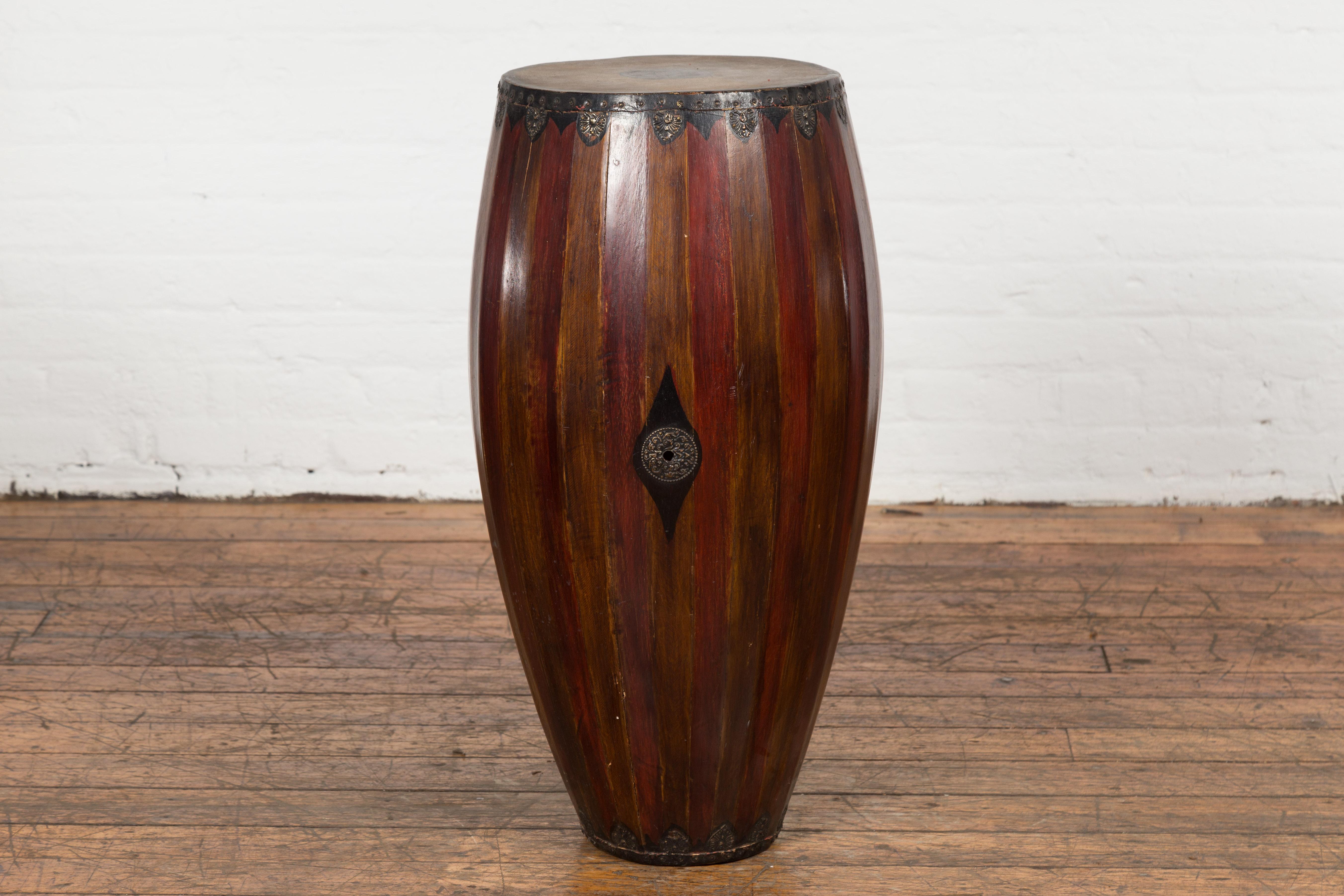 An antique Thai wood and leather two toned processional drum from the 19th century, with slatted body, butterfly motifs and weathered patina. Created in Thailand during the 19th century, this processional drum showcases a two toned structure. The