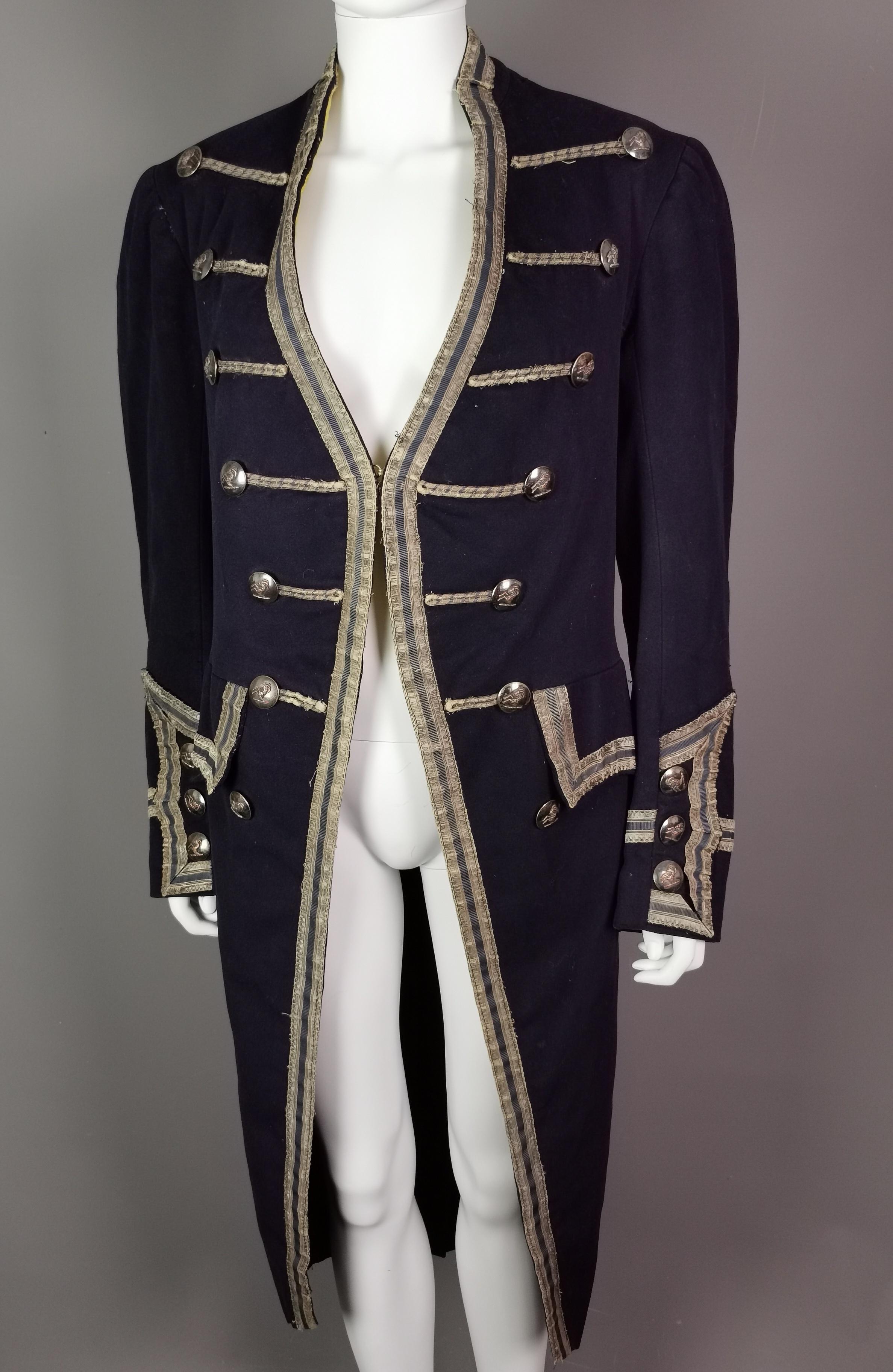 An incredible antique 18th century style military frock coat.

Made for the stage this is a theatrical garment, Edwardian era, made from a heavy navy blue wool with a medium length nap, it is decorated with beige and gold bullion braiding and piping