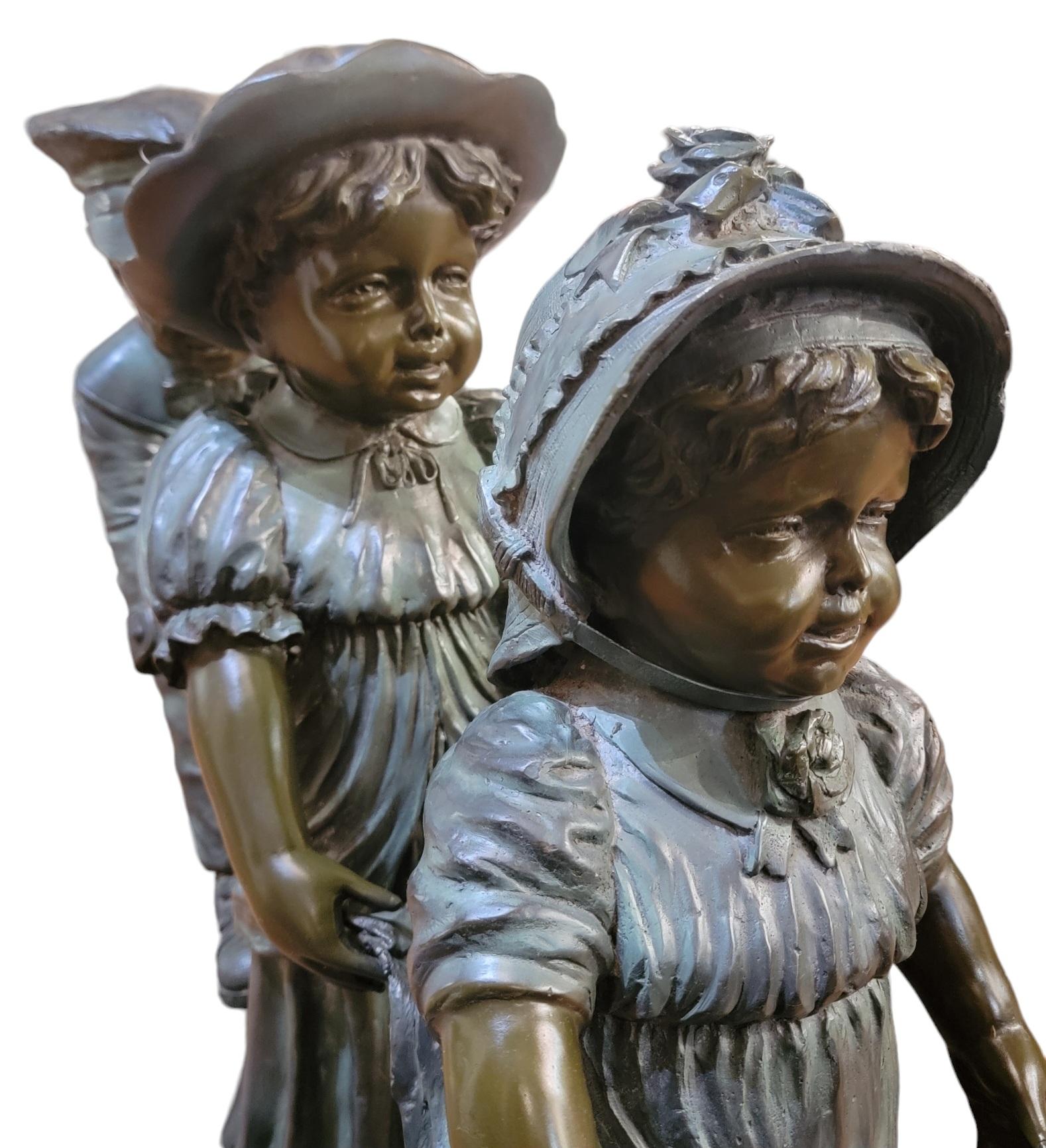 Three Children Playing Statue Signed. This playful sculpture is that of three children on a thick bronze base that is signed. The three children are from smallest to tallest, the smallest one in front. Potentially a wedding scene where the children