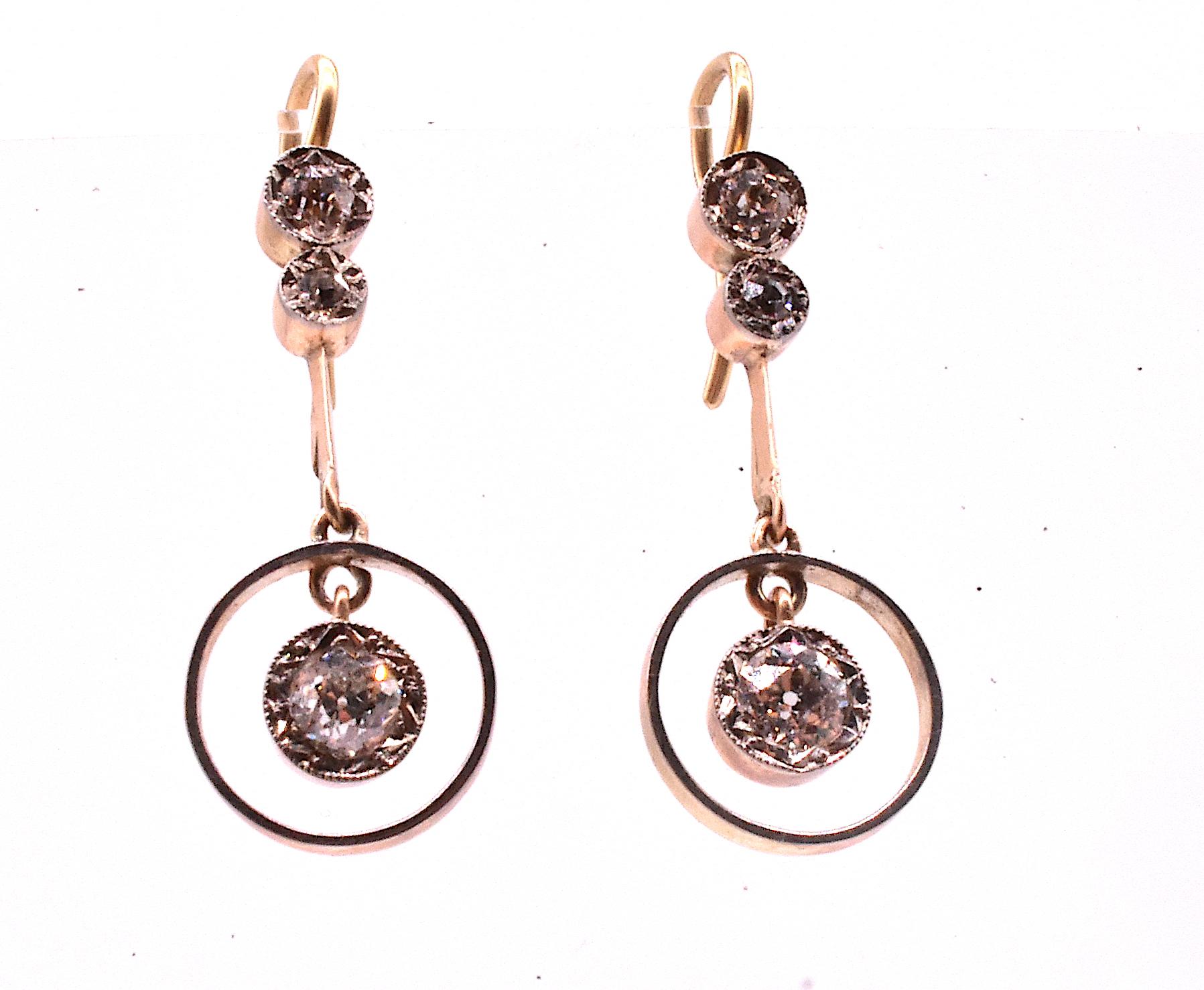 We love these charming 15K diamond and yellow and white gold earrings. Old mine cut diamonds wrapped inside a gold cylinder dance inside a concentric gold circle and shimmer in the light. Two smaller mine cuts encased in a gold cylinder are at the