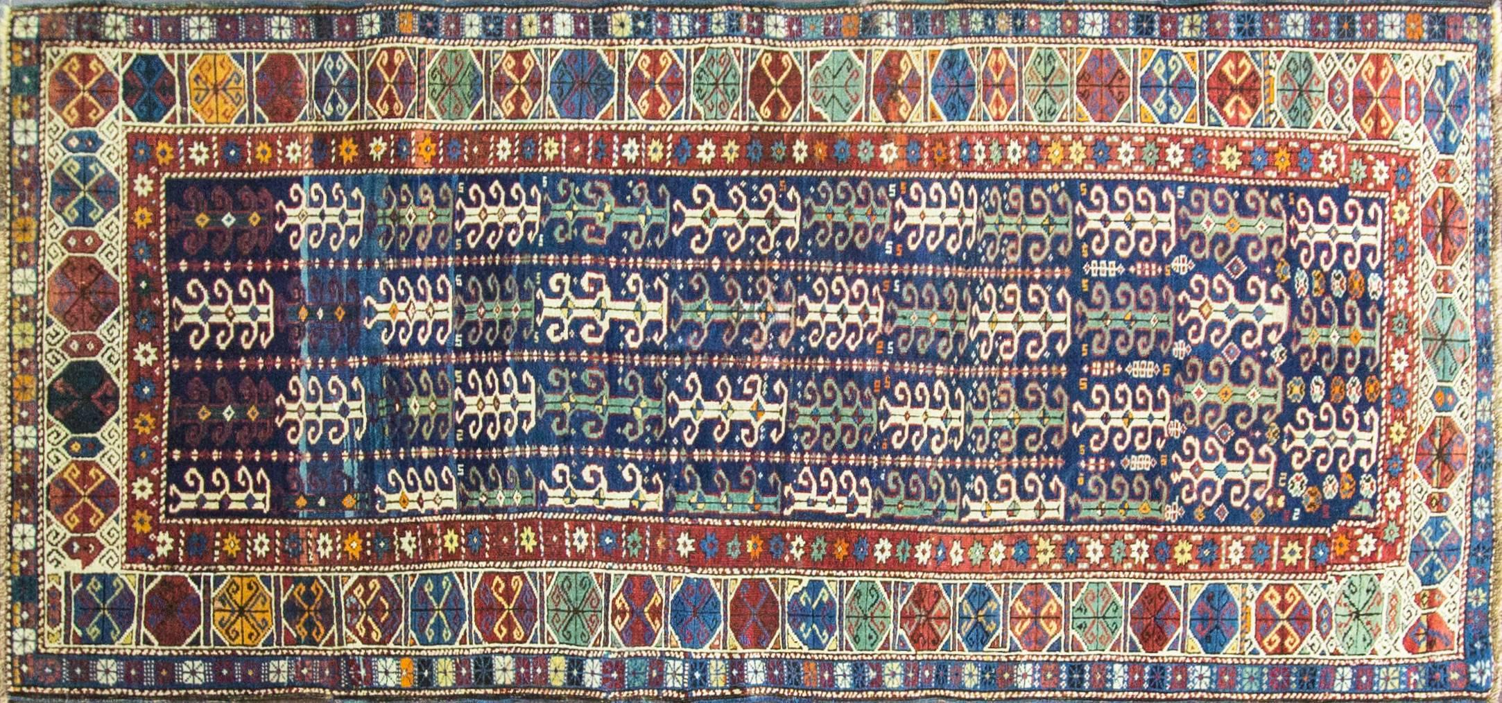 Highly unusual design antique colorful long Kazak rug.
The Caucasus is bounded by the rugged mountains and lush valleys of Armenia, Azerbaijan and Georgia. This cultural melting pot was populated by Armenian dyers and weavers, Azeri Turks, groups