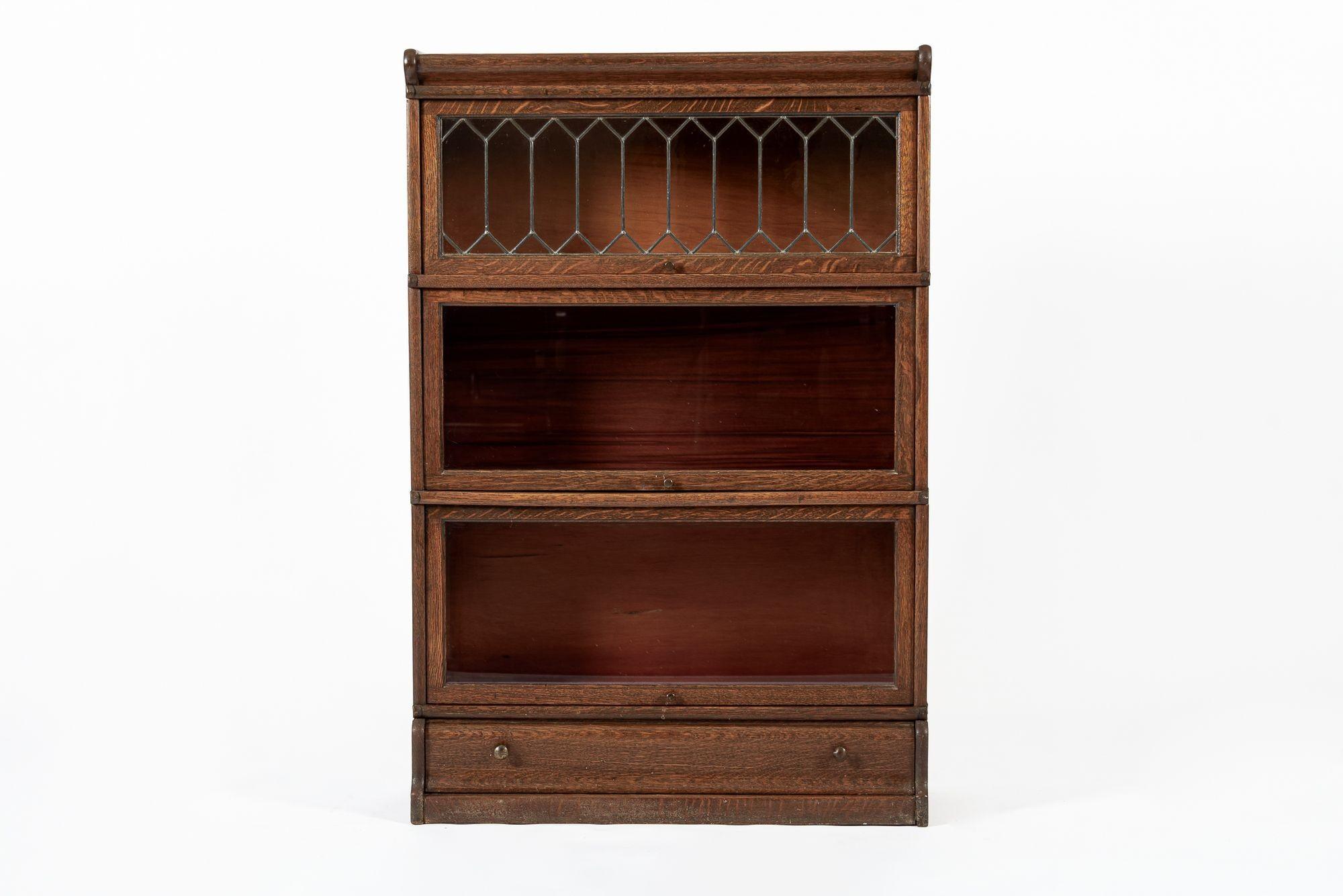 This antique mission style three stack wooden lawyer or barrister bookcase cabinet is from the early 1900s. Well-crafted from tiger oak wood, this modular bookshelf disassembles into five individual pieces including separate top and base with three
