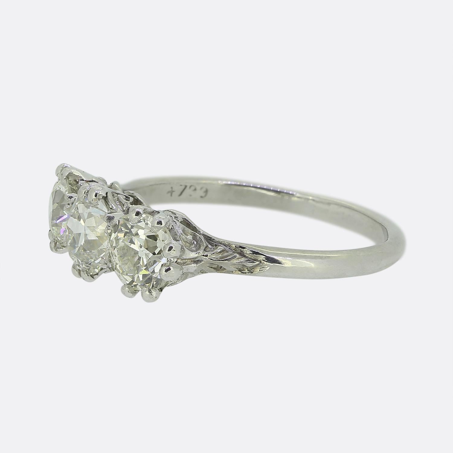 Here we have a classically styled three-stone diamond ring taken from the Edwardian period. This platinum piece features three round faceted old European cut diamonds in a single line formation across the face. Each stone has been individually claw